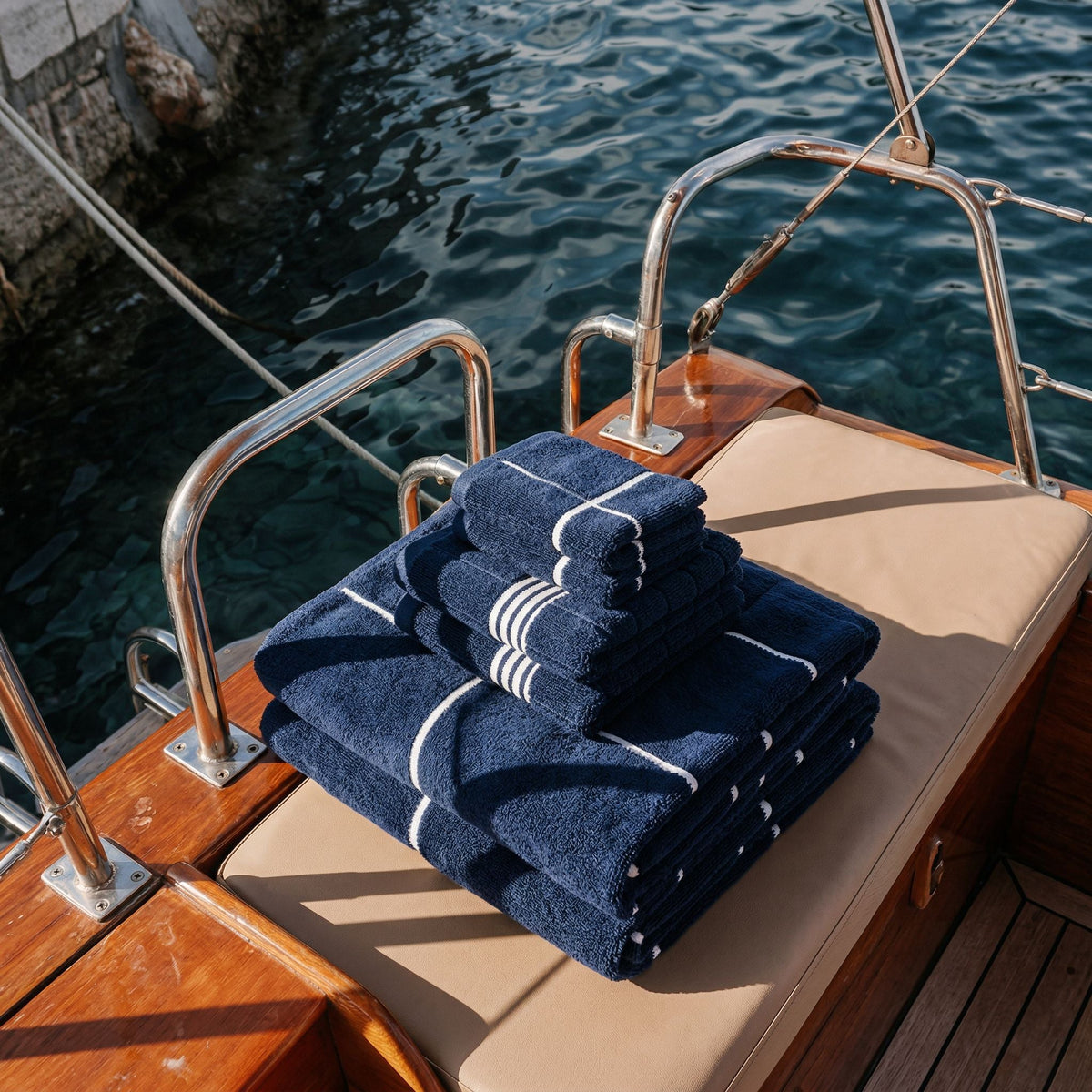 Folded navy cotton towels with white stripe bands on outdoor lounge