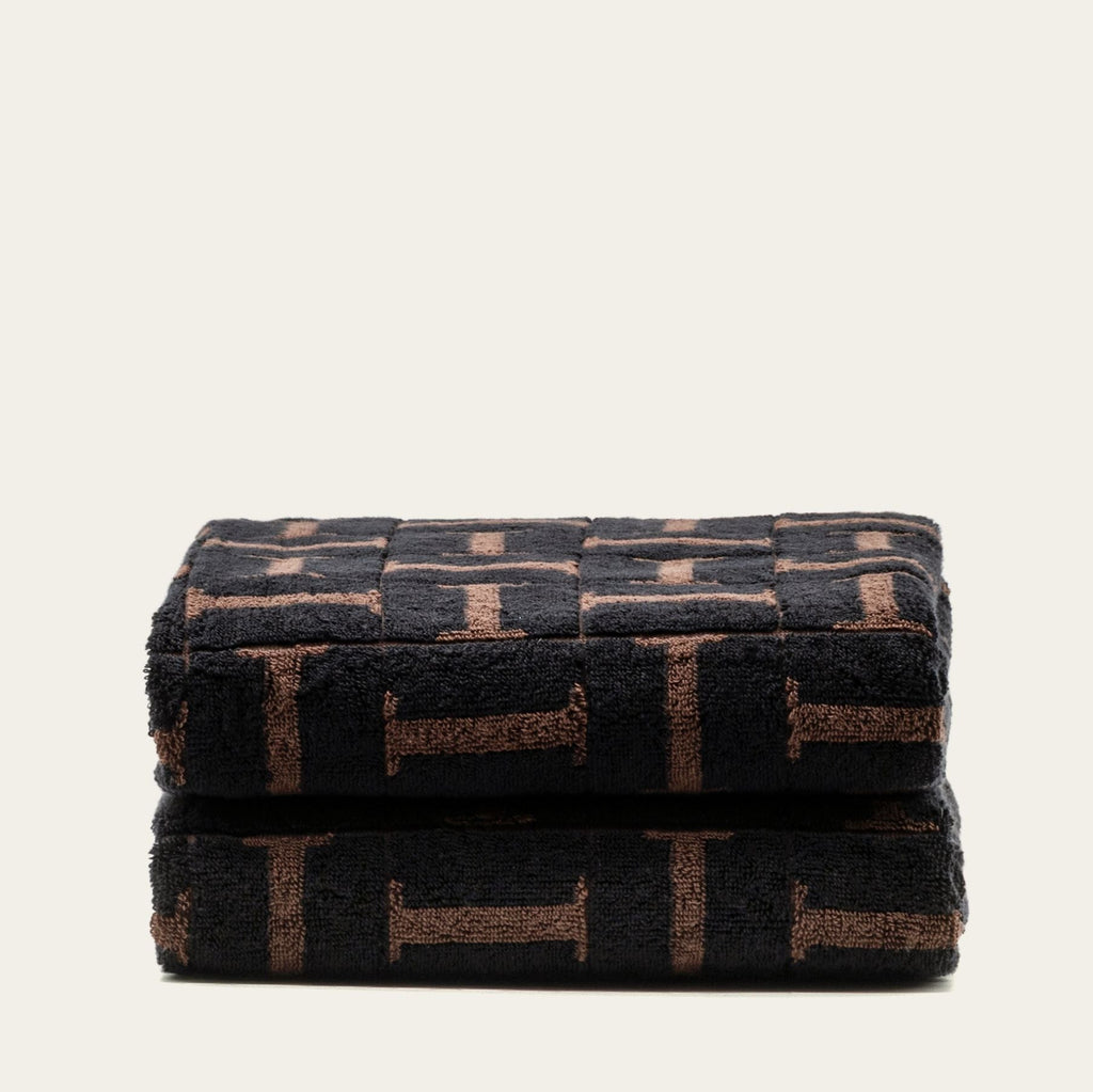 Folded cotton bath towel set in dark tobacco and black geometric pattern