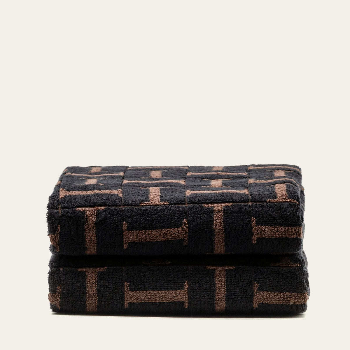 Folded cotton bath towel set in dark tobacco and black geometric pattern