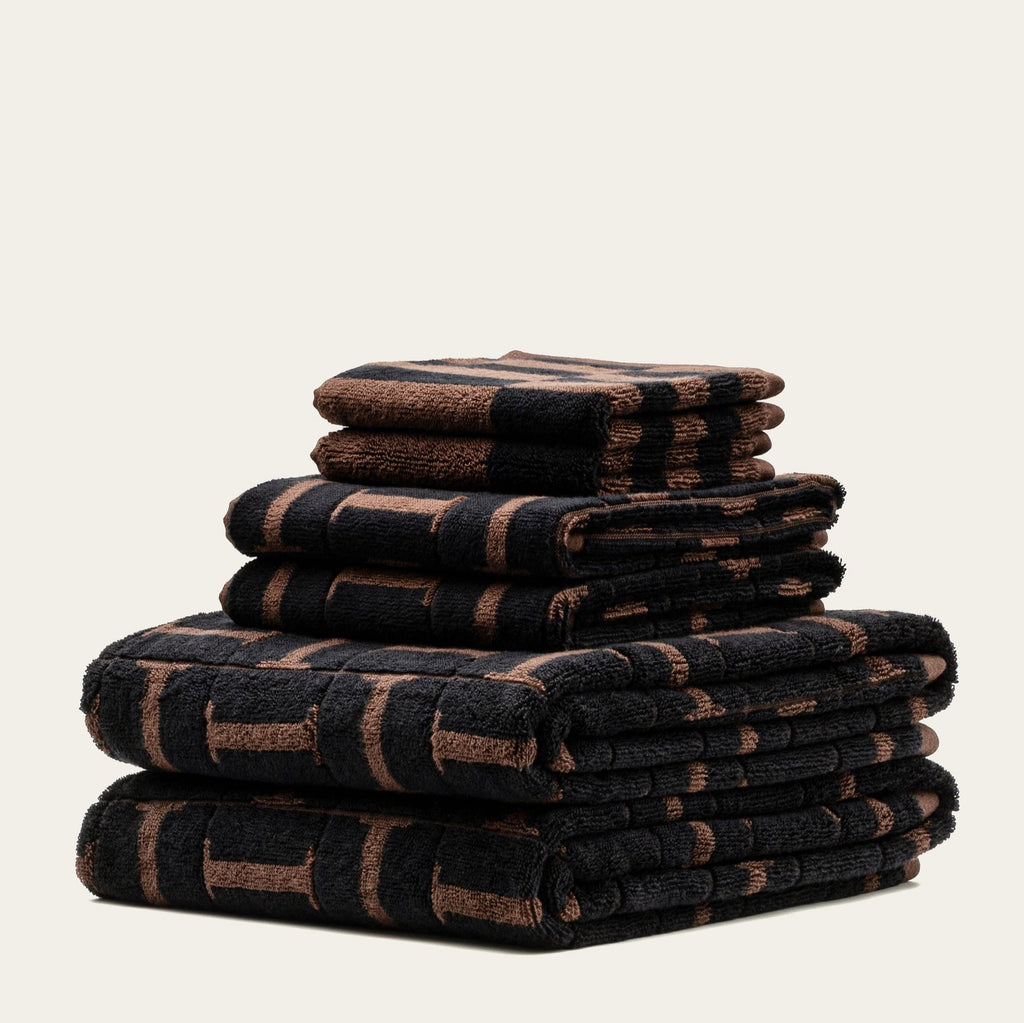 Stacked cotton towels, dark base with tobacco geometric blocks pattern