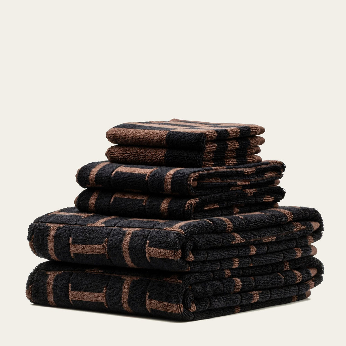 Stacked cotton towels, dark base with tobacco geometric blocks pattern