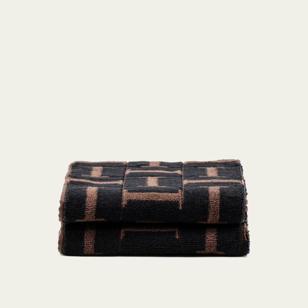 Folded cotton washcloth with tobacco and black geometric pattern, stacked
