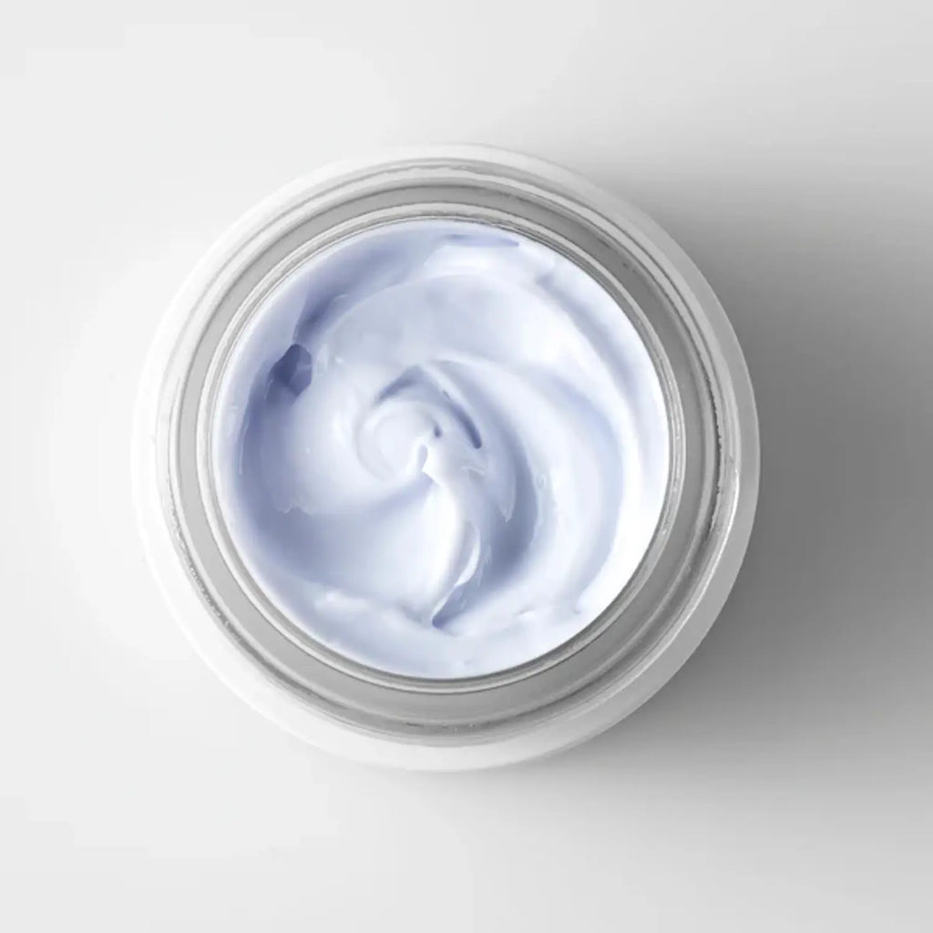 Open face cream jar showing smooth pale blue cream