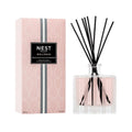 Glass diffuser bottle with pink liquid, black reeds, silver collar, NEST label