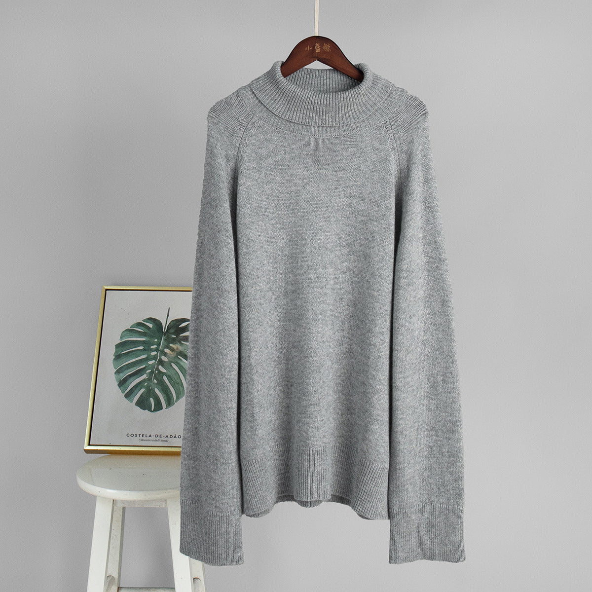 Light gray turtleneck sweater on hanger with ribbed collar and cuffs
