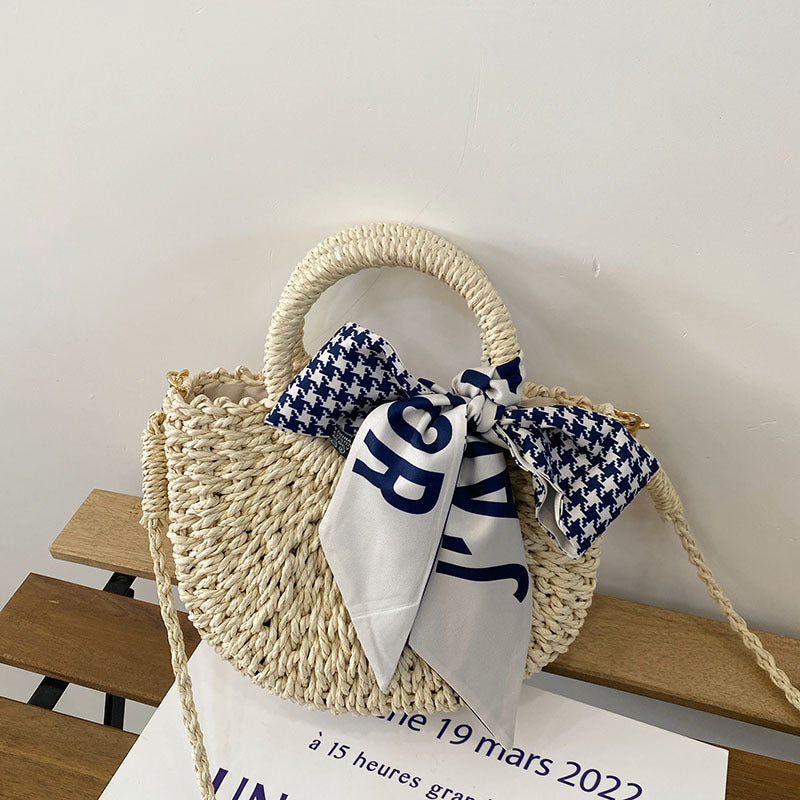 Light woven straw crossbody mini bag with blue houndstooth bow and striped scarf