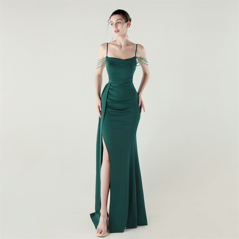 Green satin evening dress with thin spaghetti straps, beaded fringe sleeves, and side slit