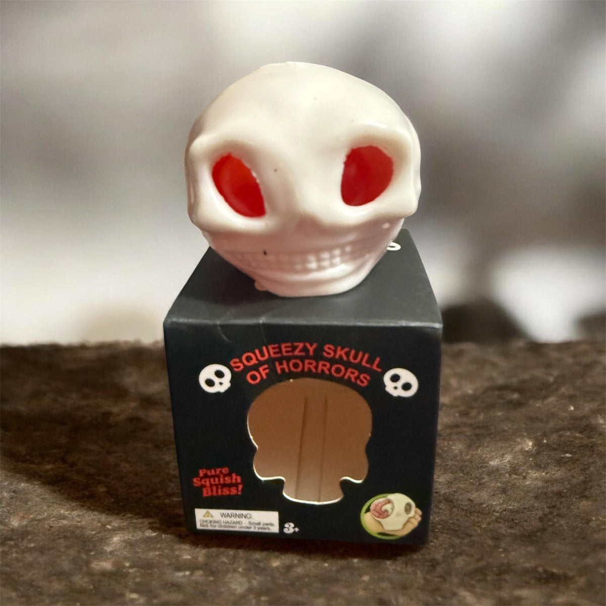Squeezable skull squish toy white skull on black display box