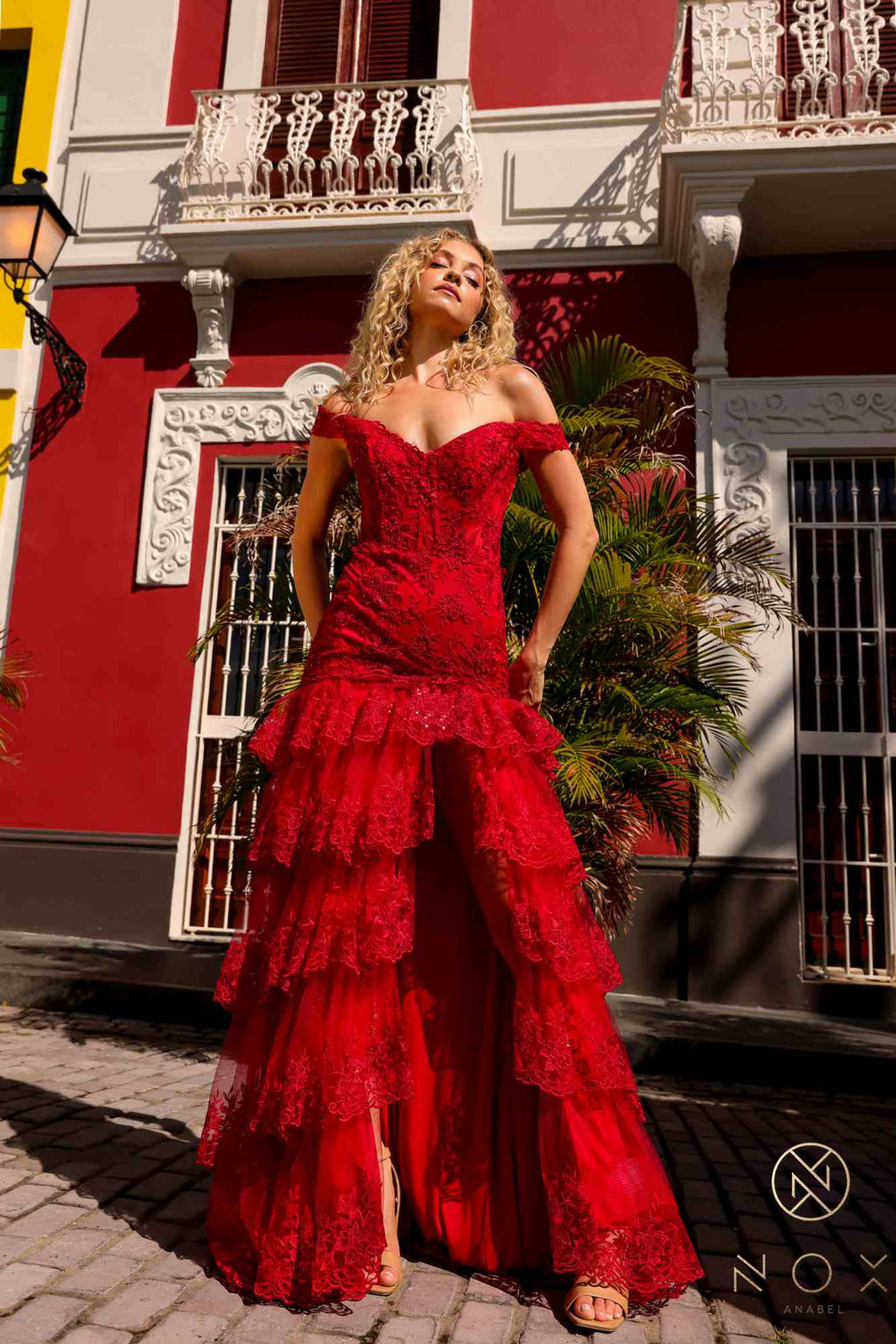 Red off-shoulder corset dress with layered ruffle tiers and long flowing hem.