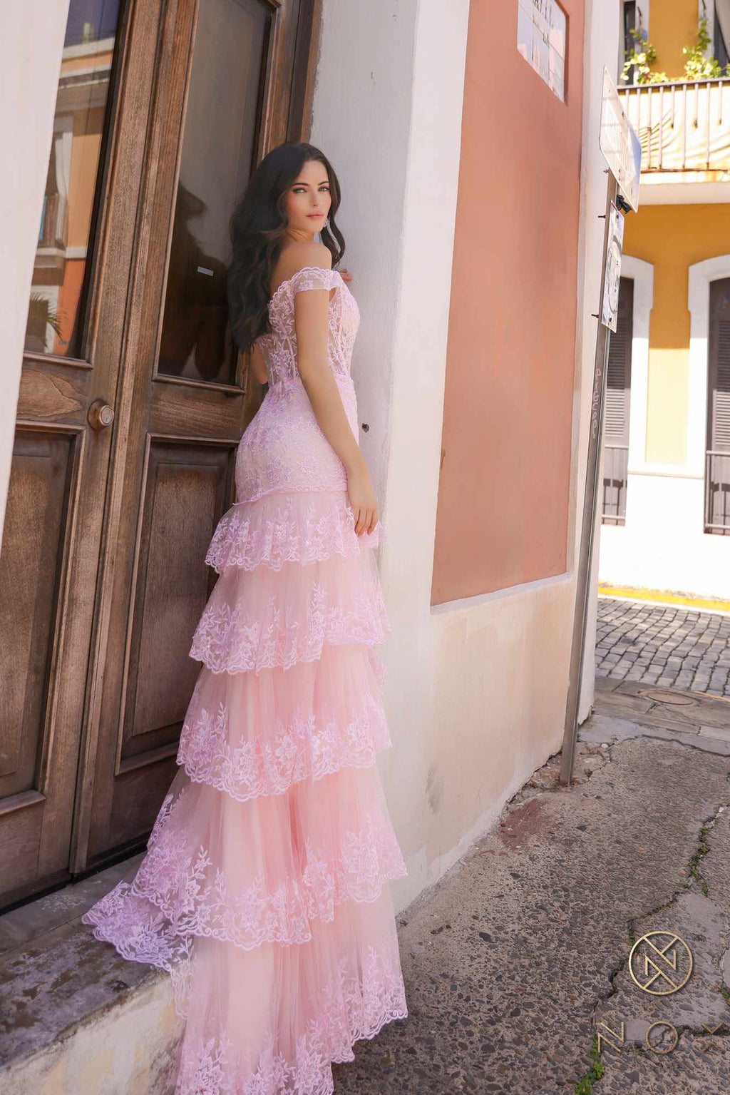 Blush off-shoulder corset dress with layered tiered ruffles and high slit, standing side view