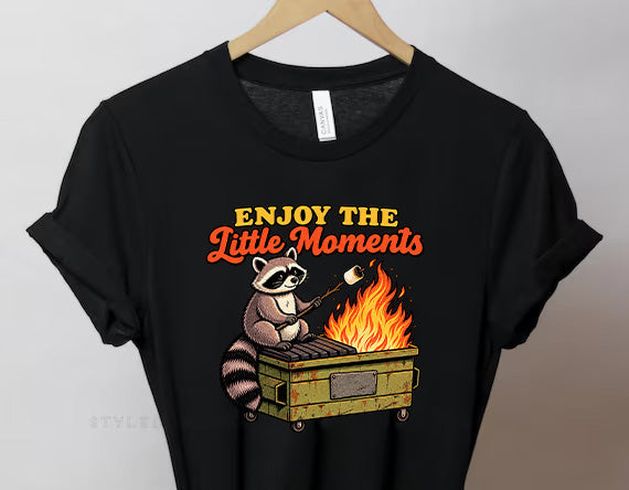 Black graphic tee with Enjoy the Little Moments text and raccoon flame illustration