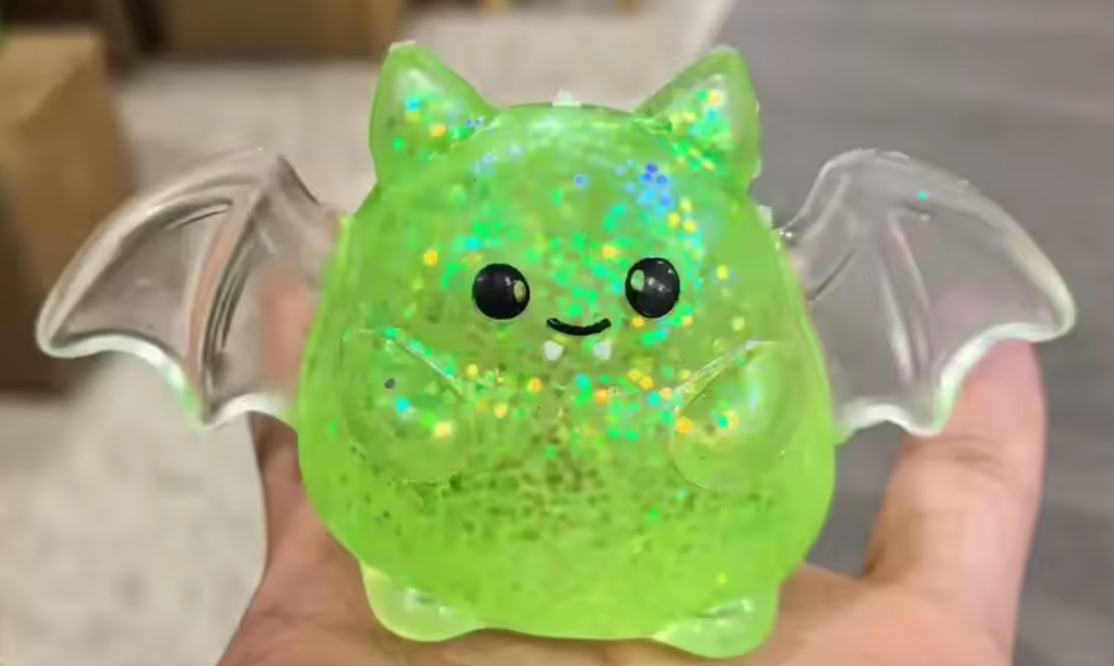 Glittery green bat squishy with friendly smile, winged shape, firm rebound