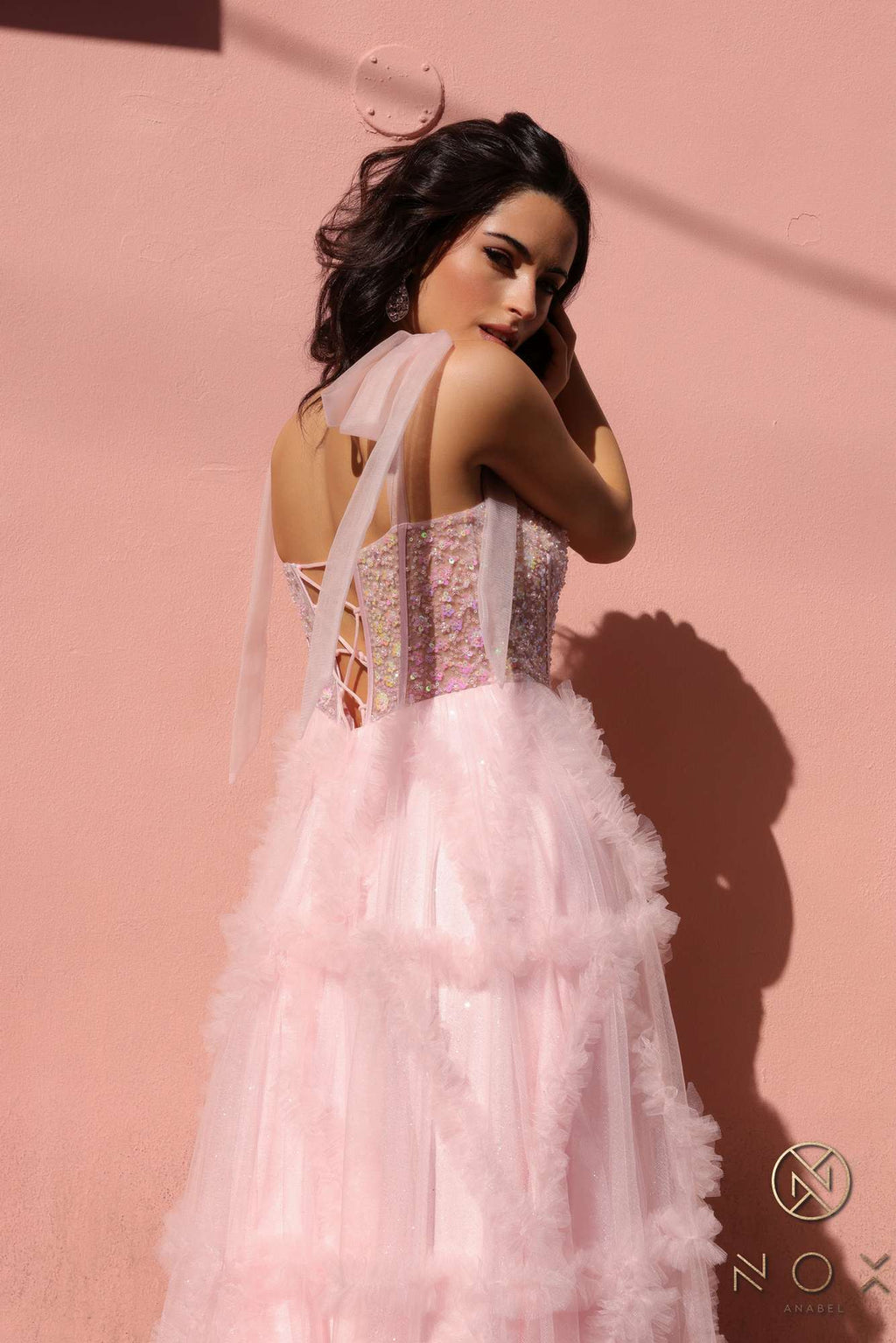 Blush pink A-line gown with corset bodice, ribbon shoulder ties, and layered ruffle skirt