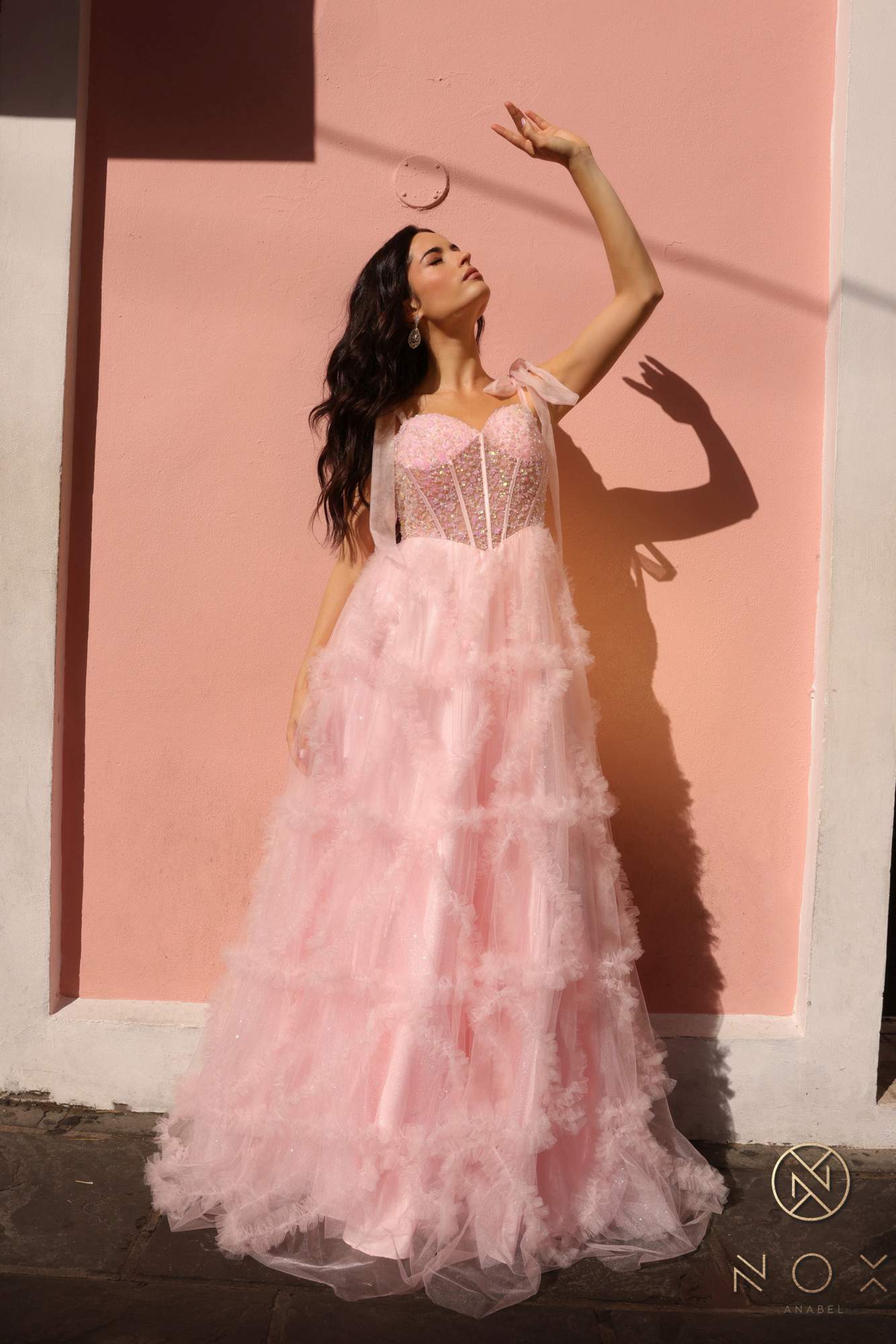 Blush pink long A-line gown with corset bodice, ribbon straps, and layered ruffles