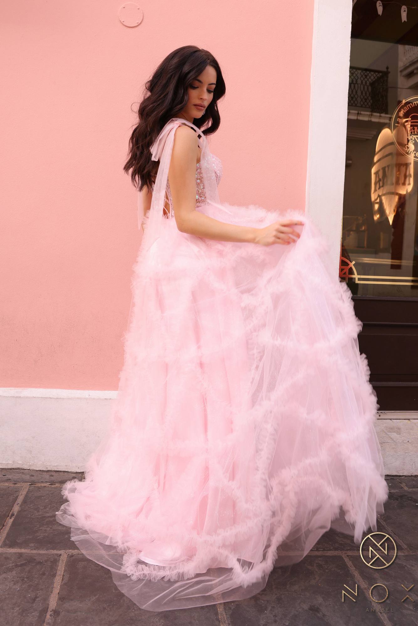 Blush pink A-line gown with ribbon straps and cascading layered ruffle skirt