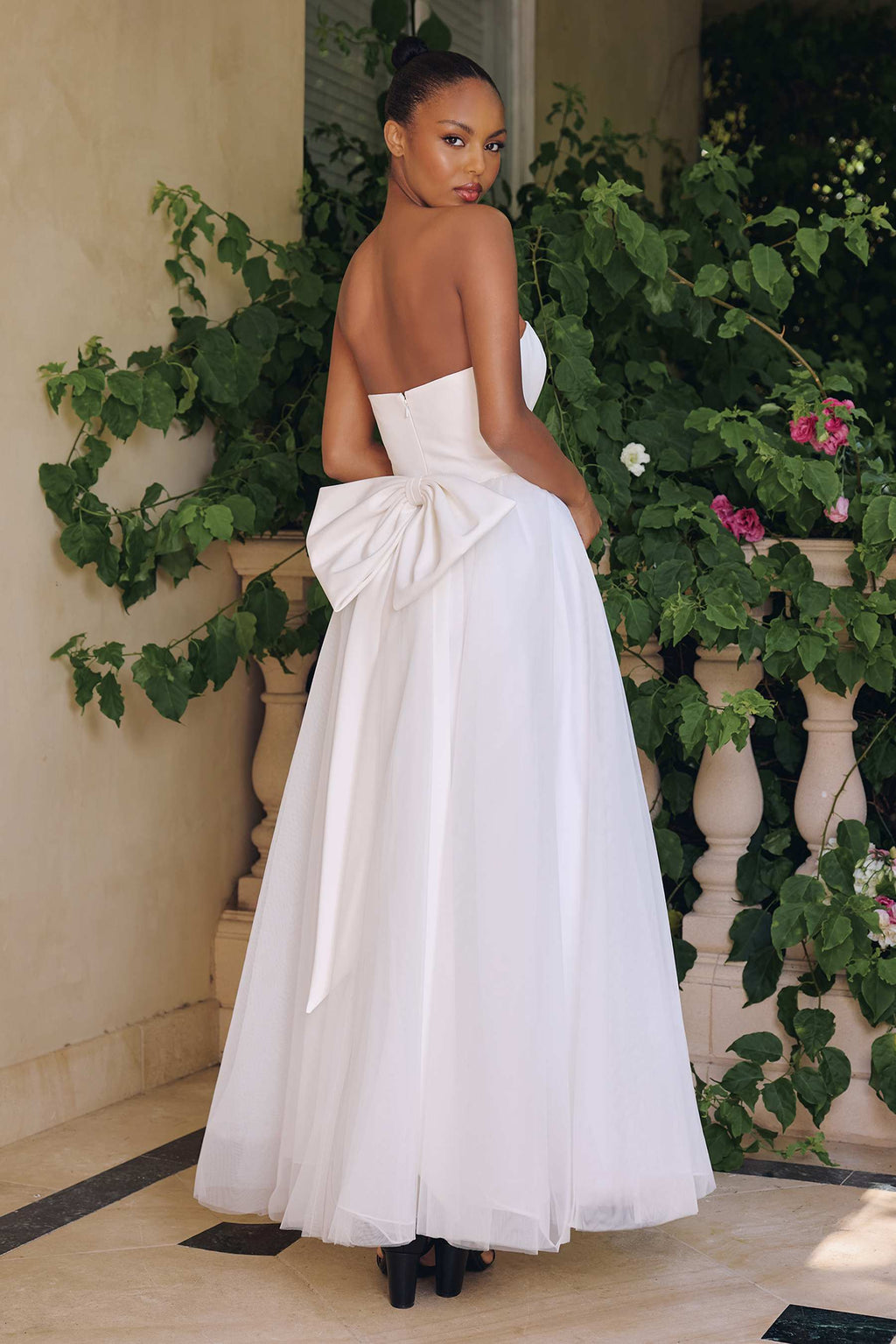 Off-white strapless bridal gown, draped back with bow detail and full A-line tulle skirt