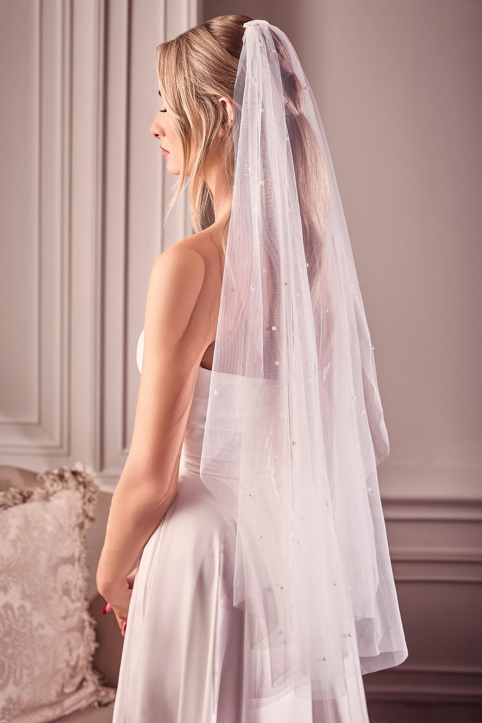 Off-white fingertip bridal veil draped over shoulders with pearl-like bead details