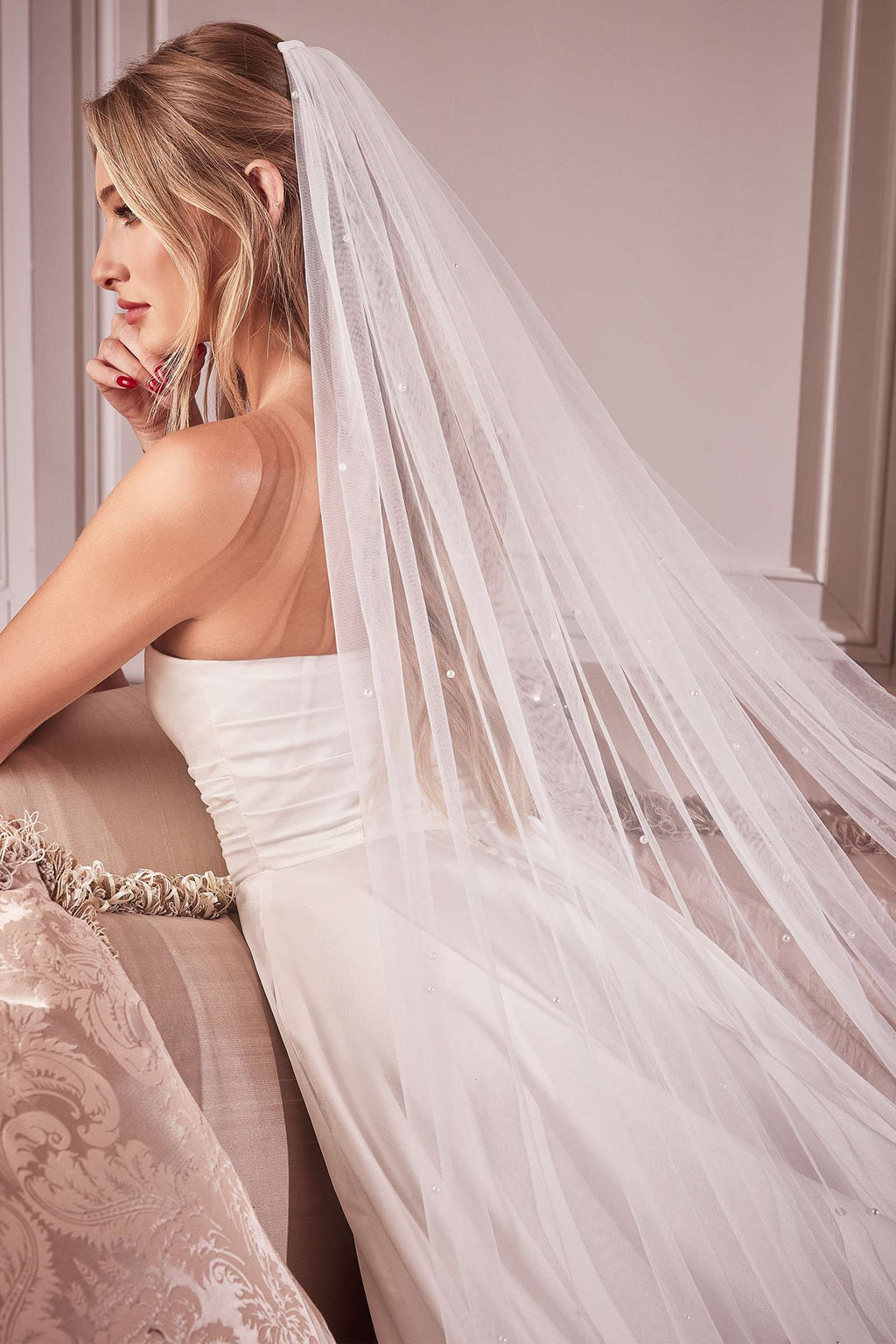 Off-white bridal veil with pearl trim, draped over shoulder and back