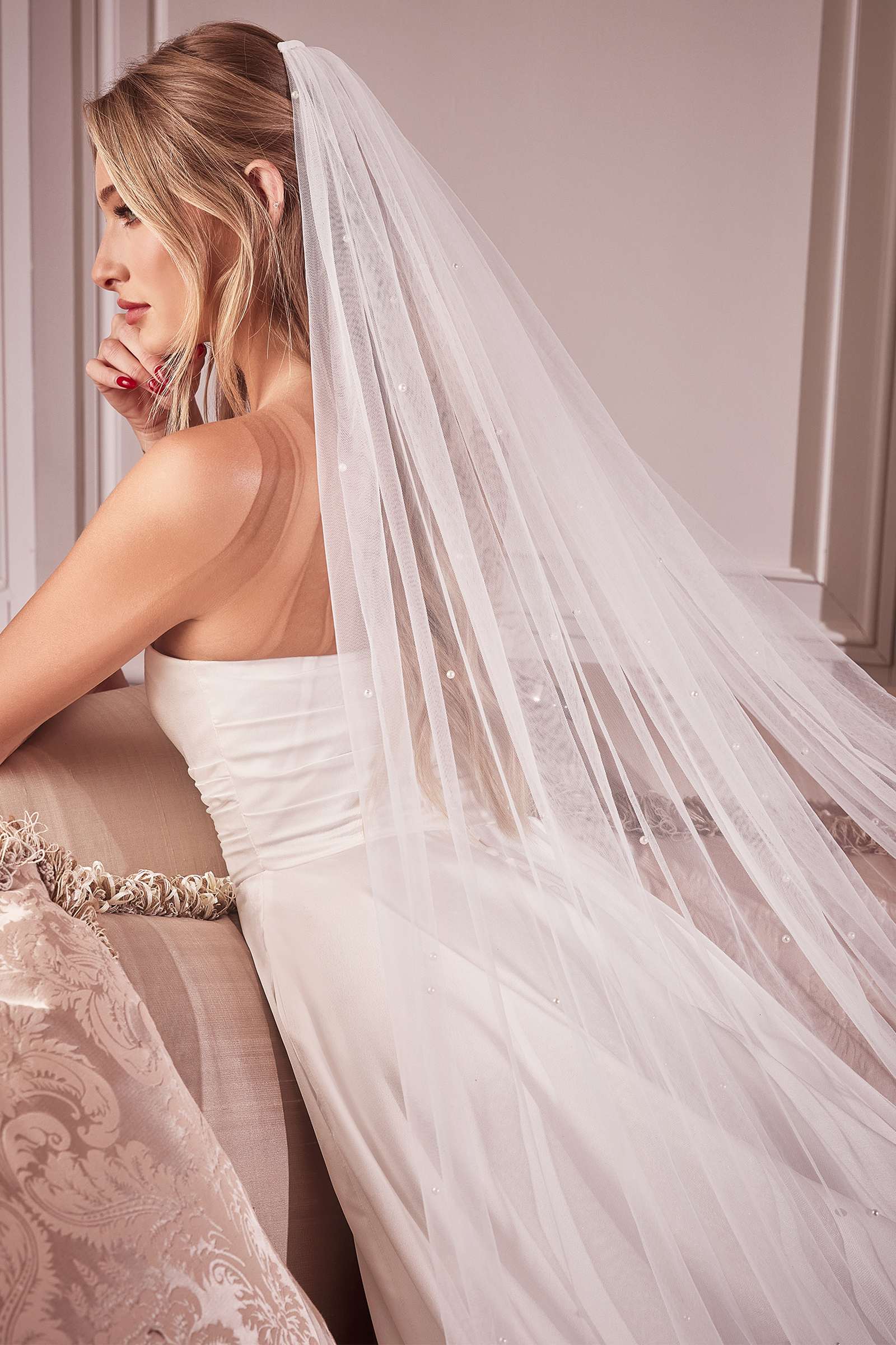 Off-white bridal veil with pearl trim, draped over shoulder and back