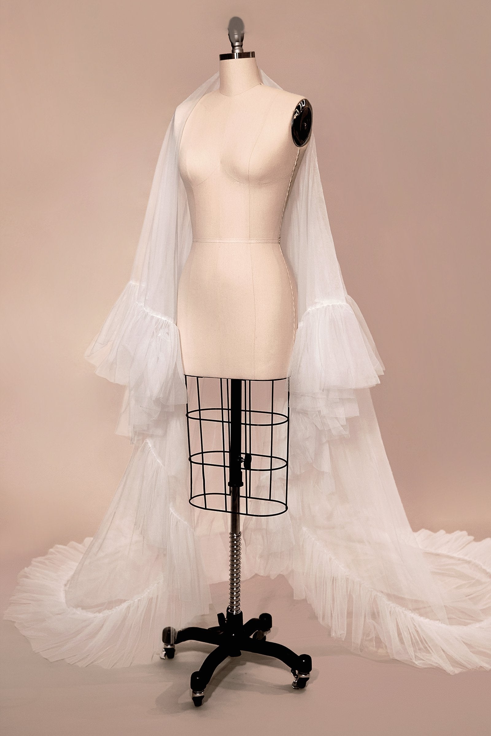 Off-white two-tier ruffle-edge bridal veil on a dress form, full drape