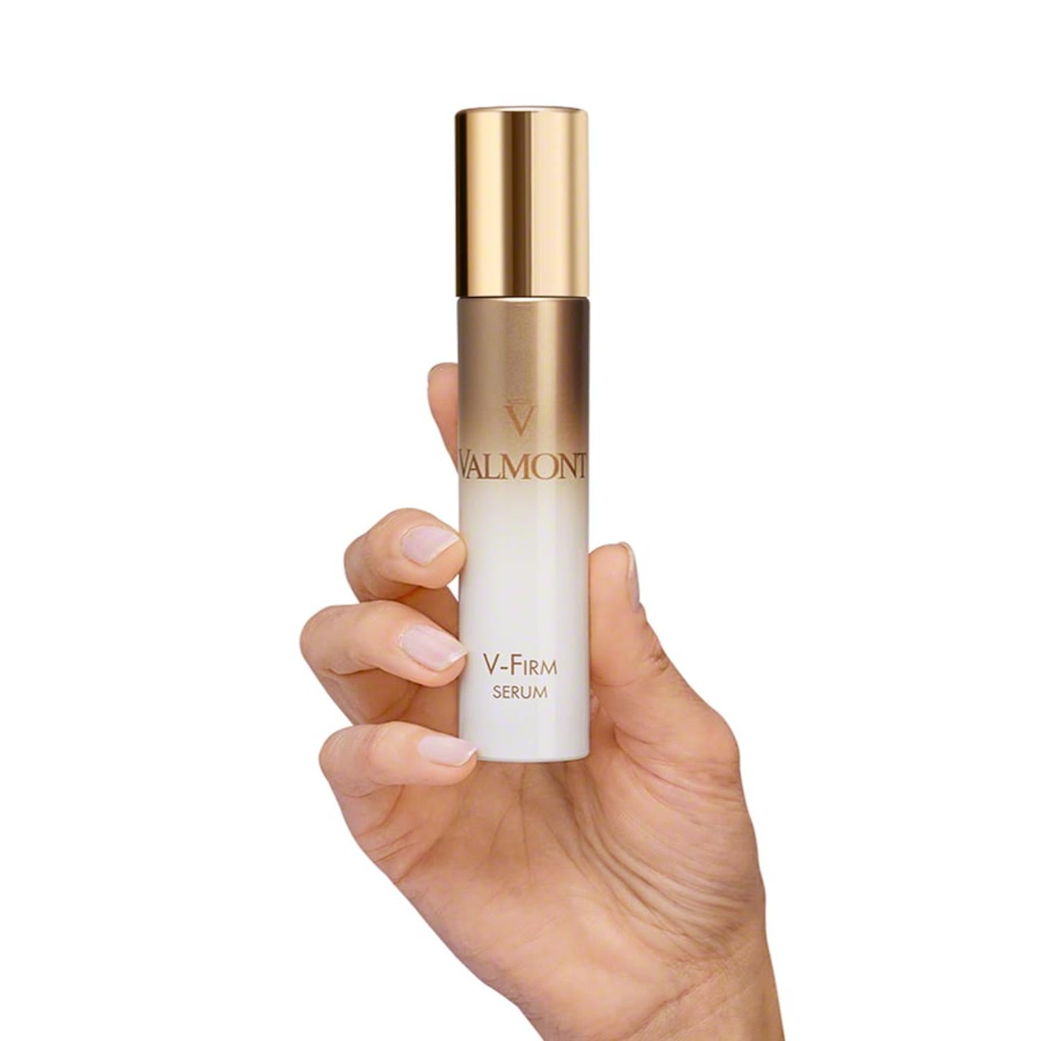 Valmont V-Firm serum bottle held in hand, gold cap and white body