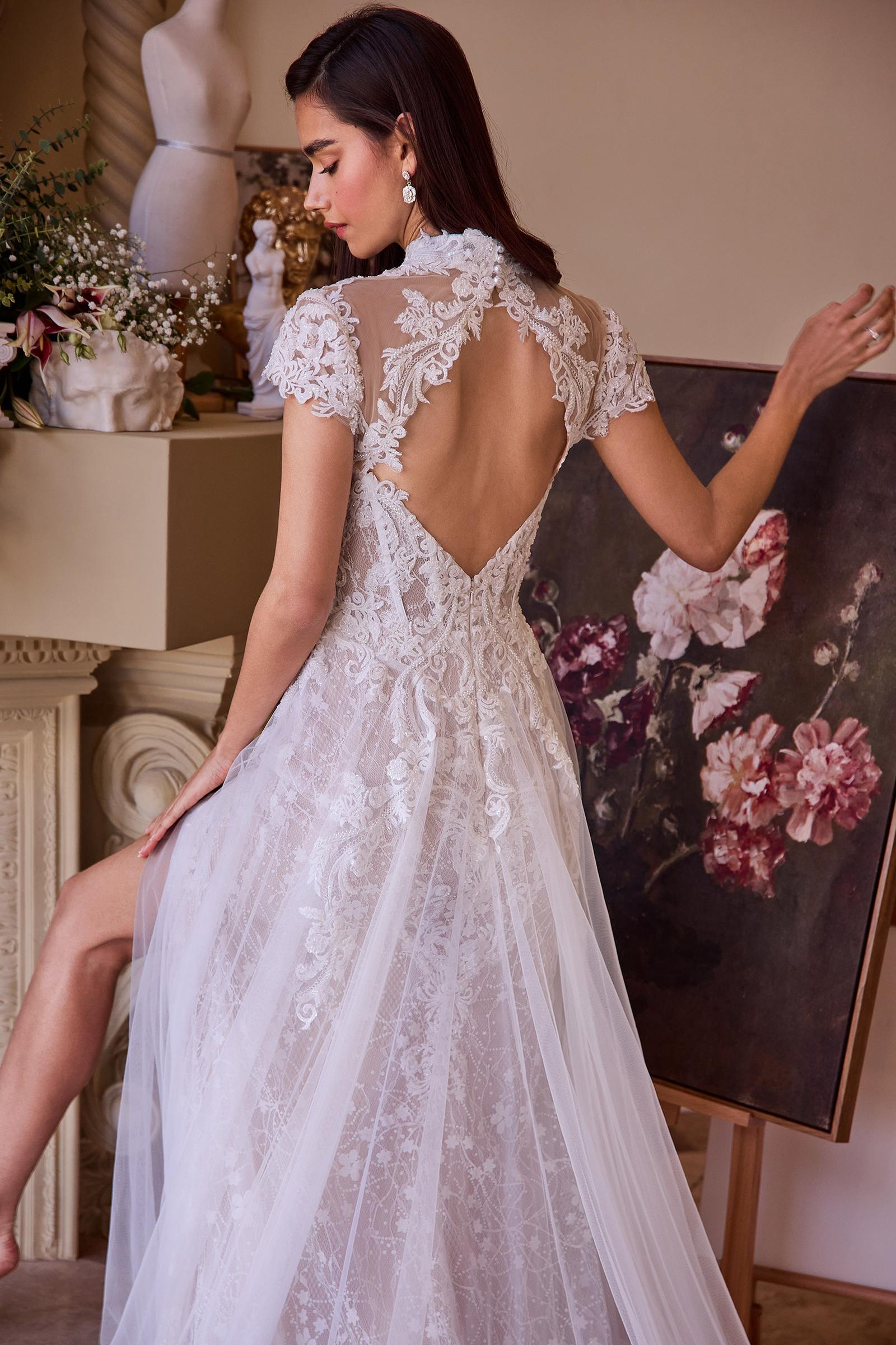 Off-white lace wedding dress with open back, short sleeves, and flowing tulle skirt