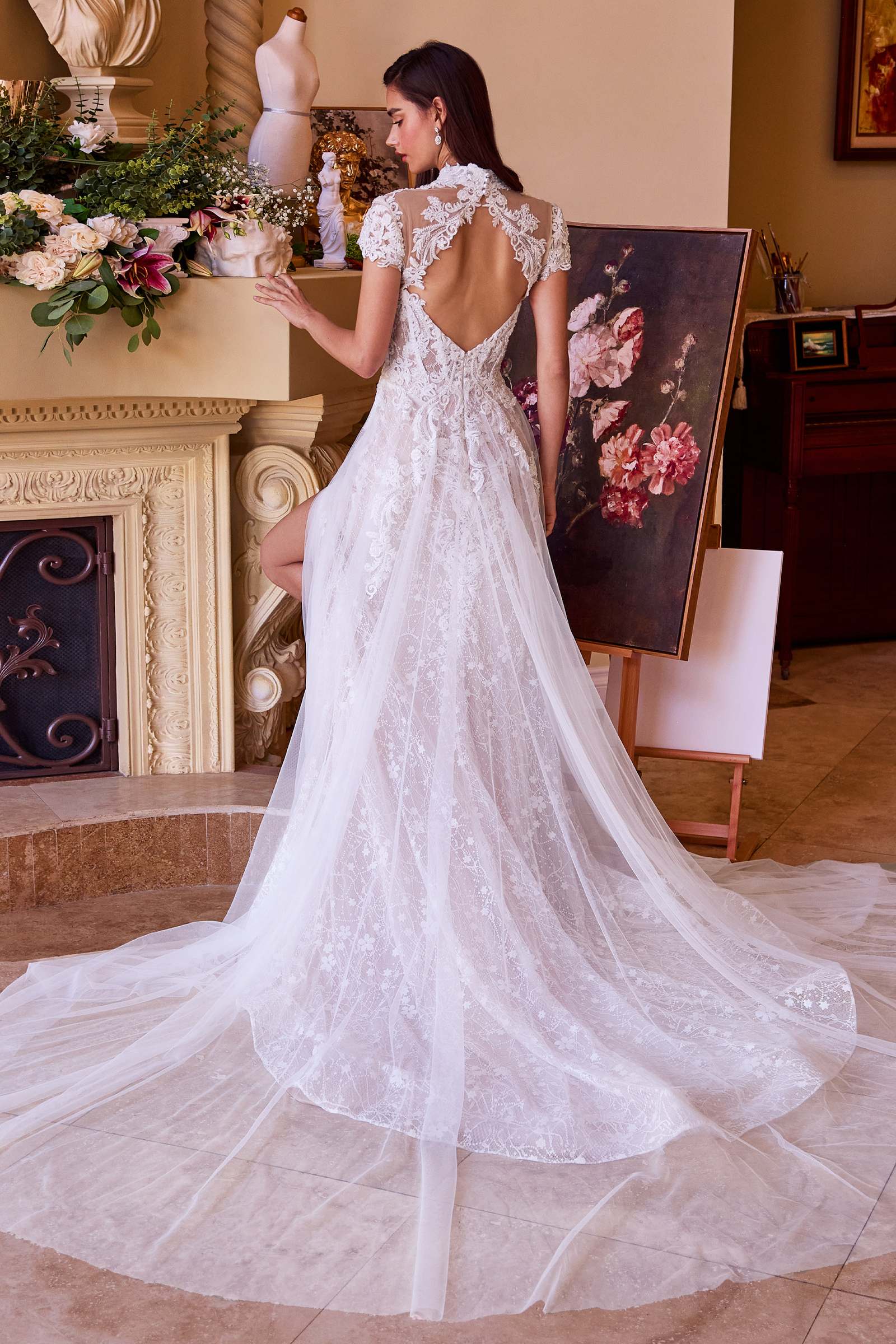 Off-white lace wedding dress with open back and floral lace cap sleeves, full tulle skirt