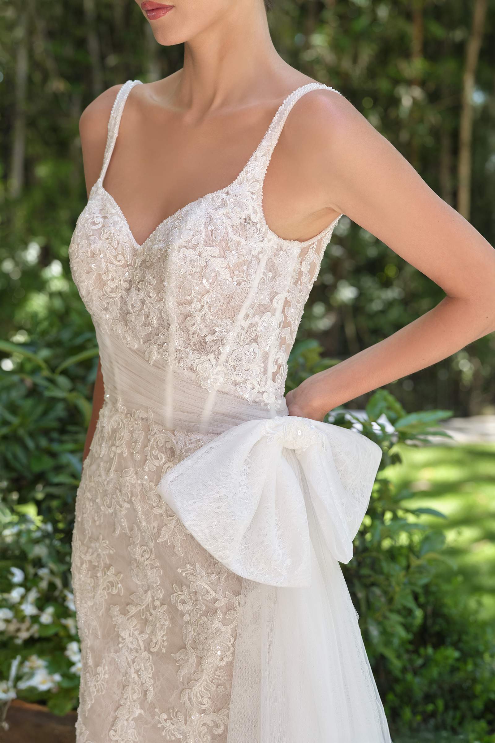 Off-white lace fitted bodice with sweetheart neckline, thin straps, tulle rosette at waist