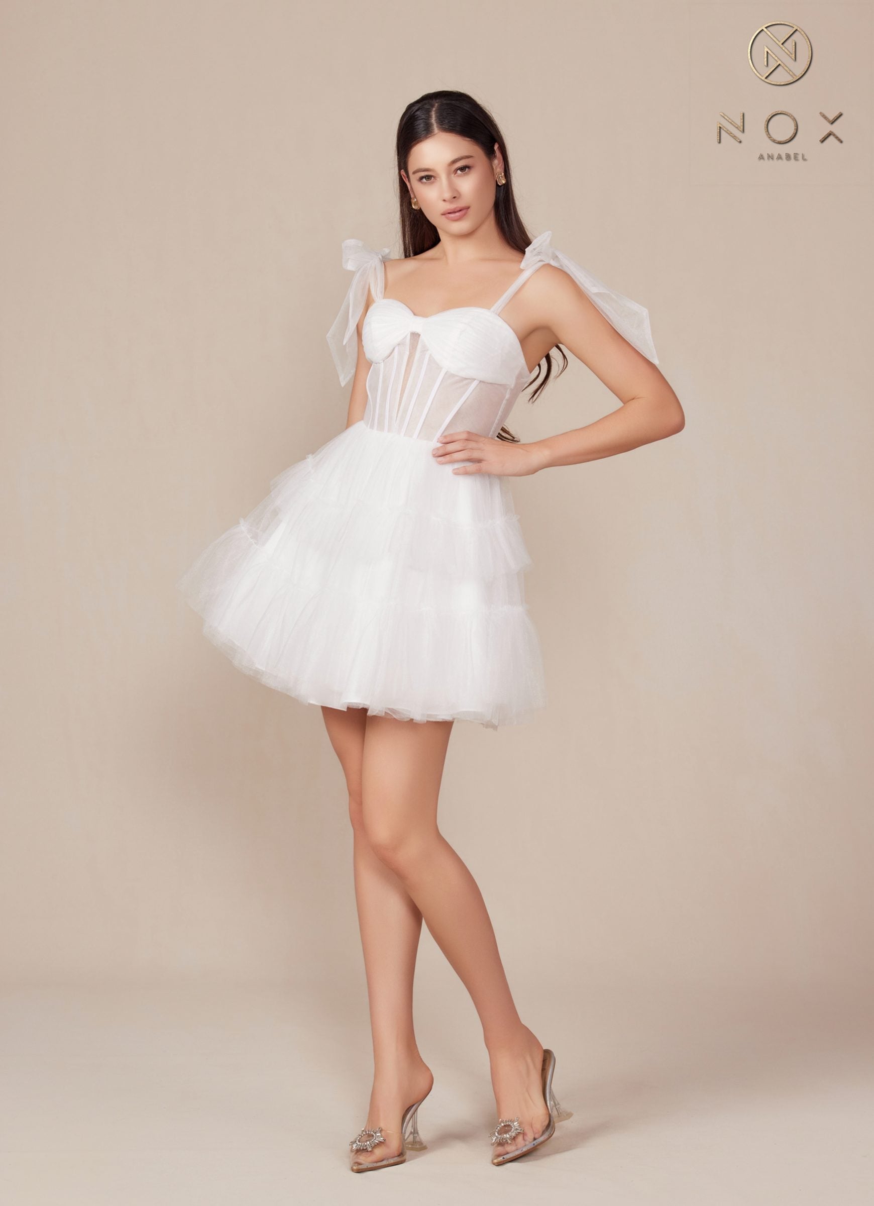 White A-line tulle dress with sweetheart bodice, bow straps, tiered ruffle skirt, hand on hip