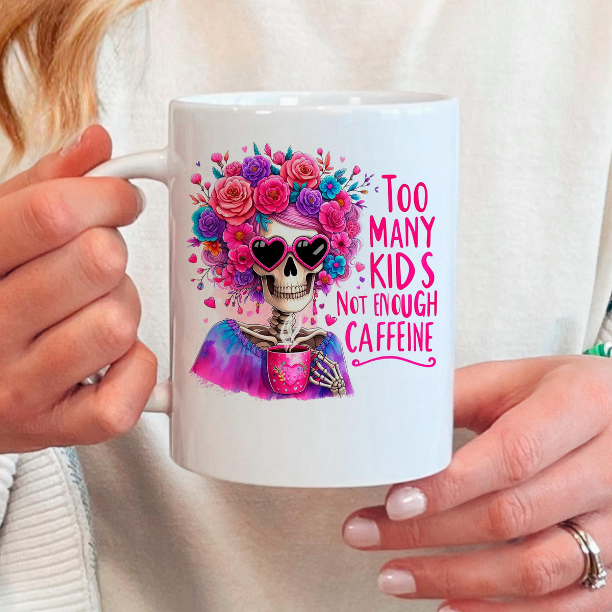 White ceramic coffee mug with floral crown skull graphic and pink text