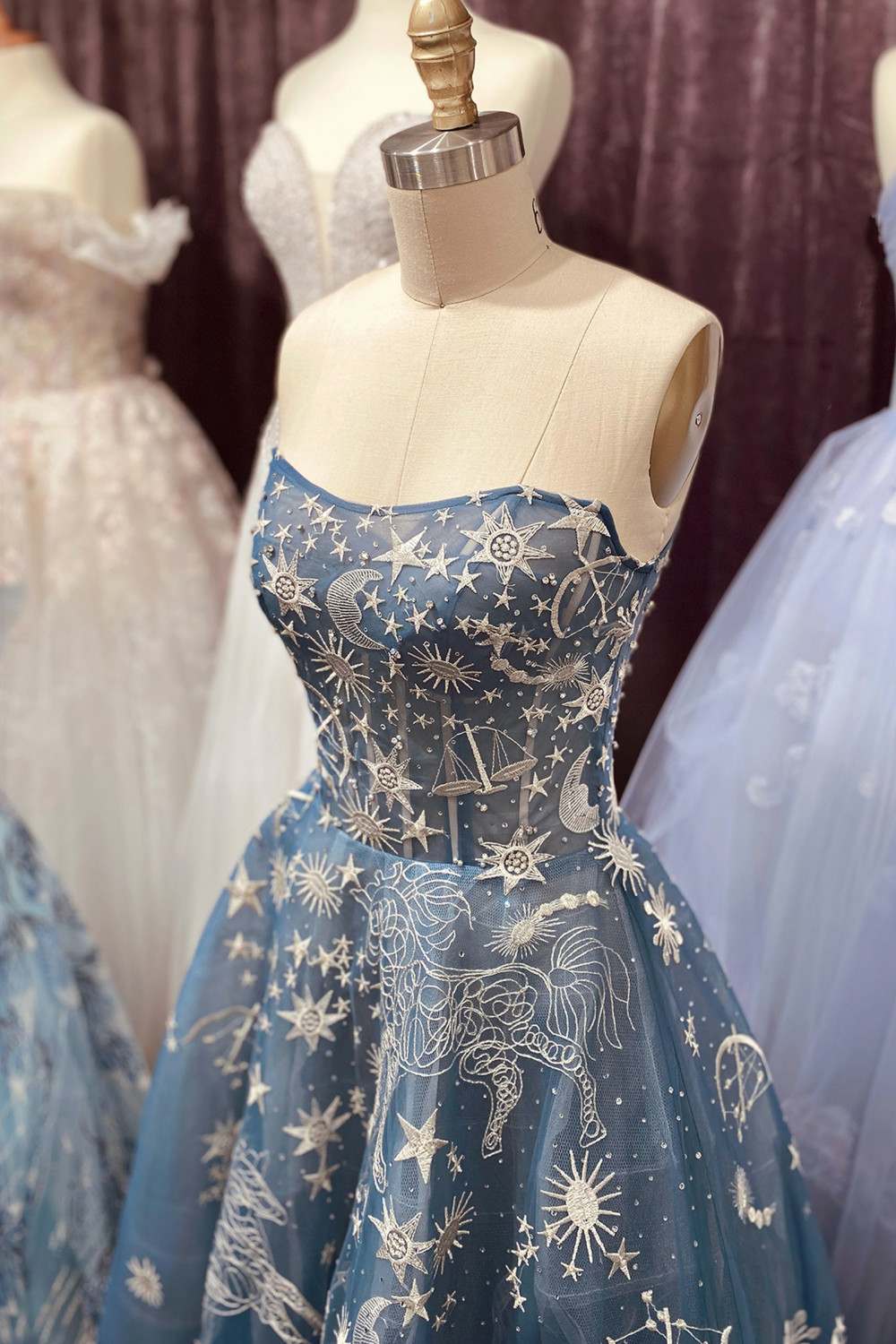Strapless long dress on mannequin in dark blue with gold star constellation embroidery