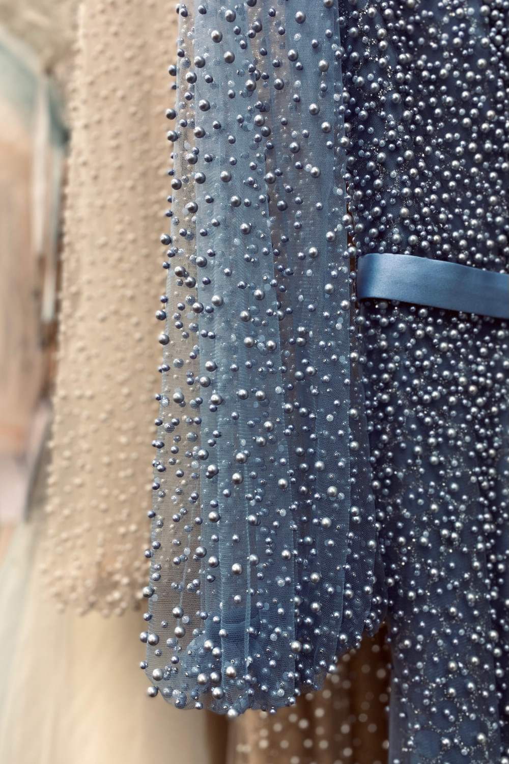 Close-up of pearl beading on a long-sleeve dress, dark blue and light fabric