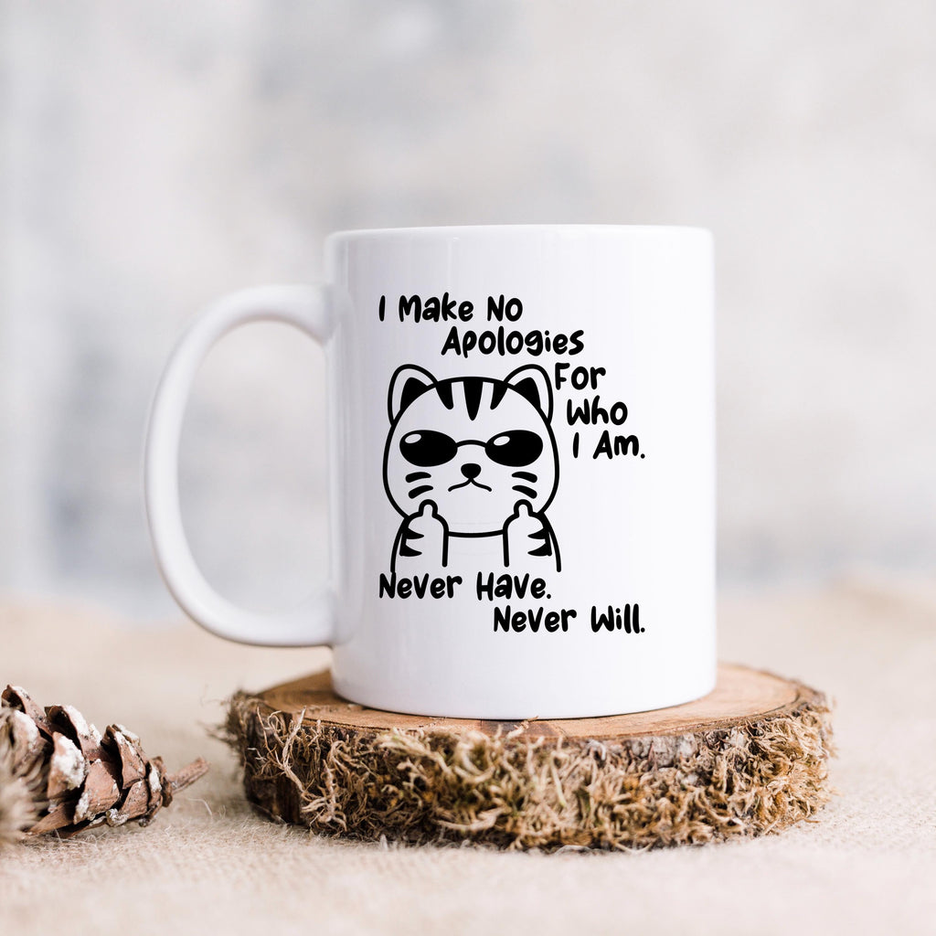 White ceramic coffee mug with black cat illustration and the quote “I Make No Apologies for Who I Am.”