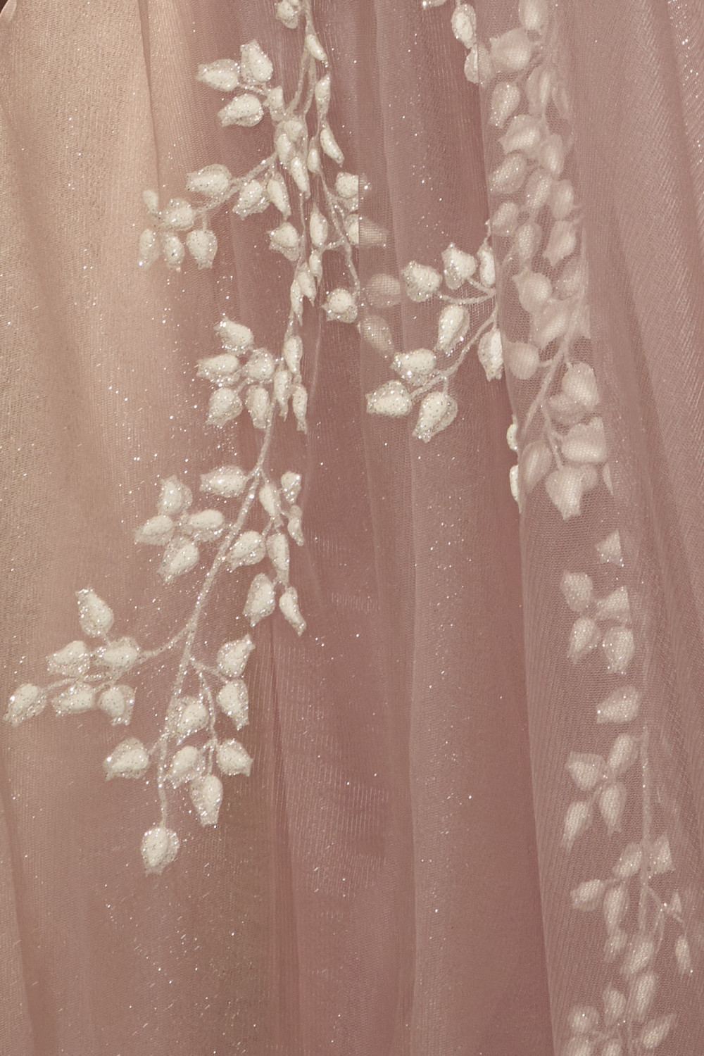Close-up: light pink sheer fabric with white floral bead appliques
