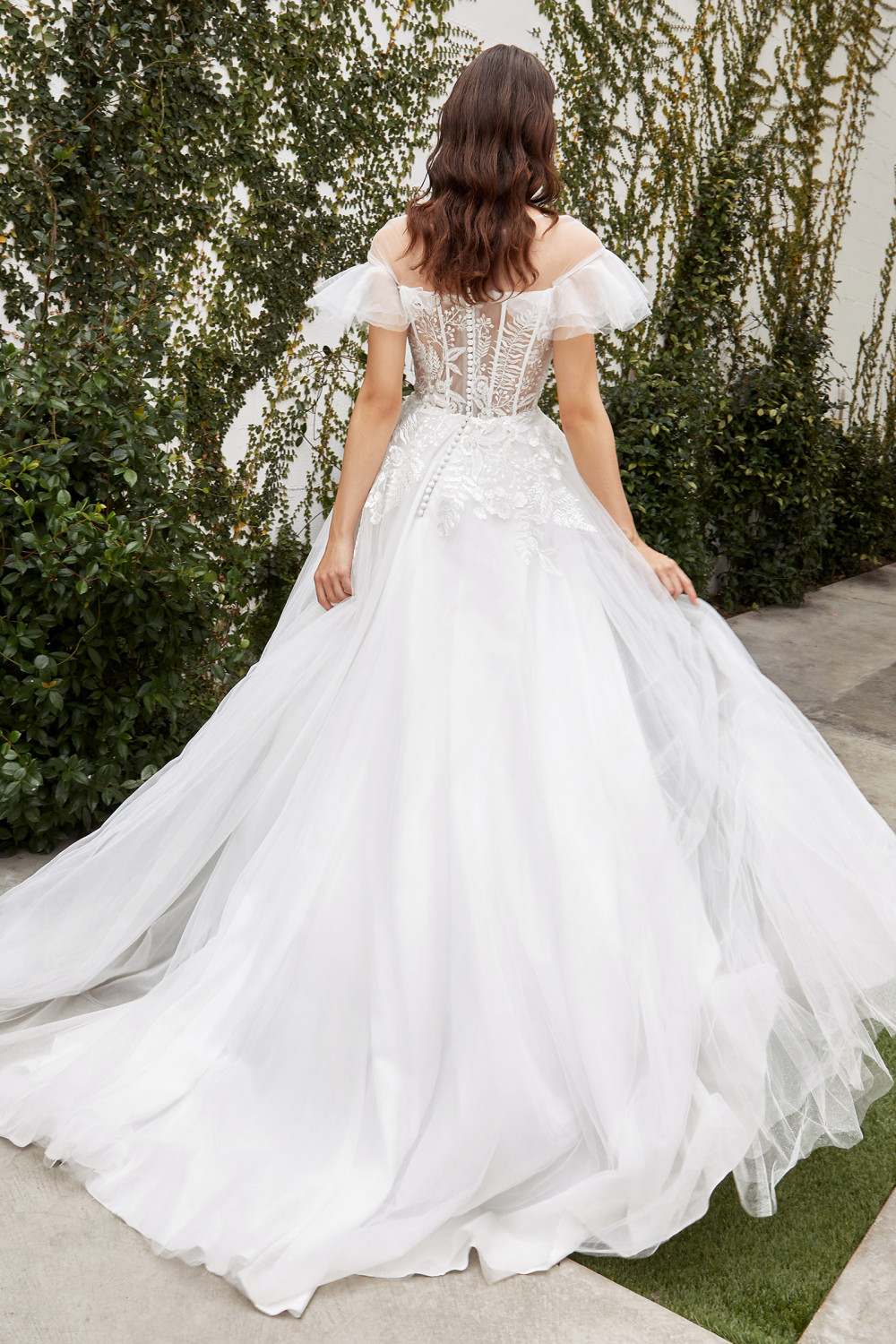 Off-white A-line wedding gown, lace corset back, sheer cap sleeves, and flowing tulle skirt