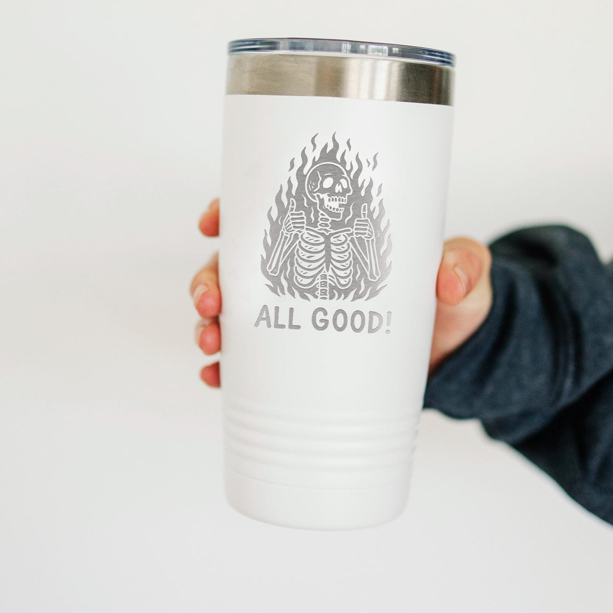 White insulated travel tumbler with stainless lid, held by hand; “All Good!” skeleton graphic