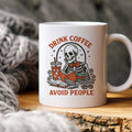 White coffee mug with skeleton graphic and red 'Drink coffee' and 'Avoid people' text