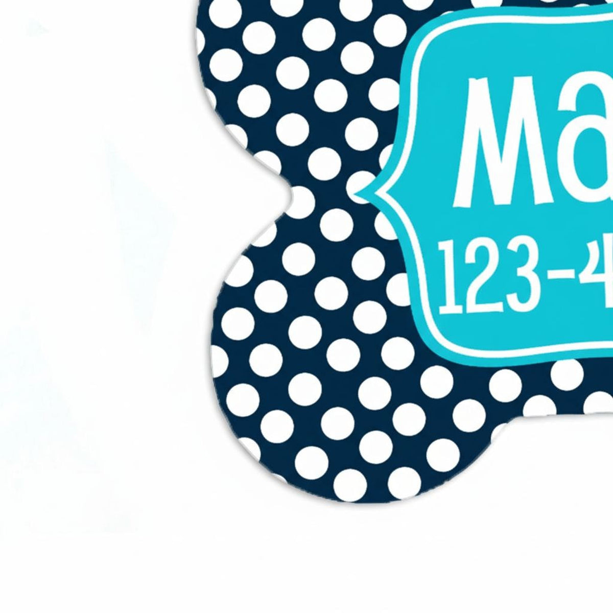 Close-up navy dog ID tag with big white dots and teal nameplate with phone number