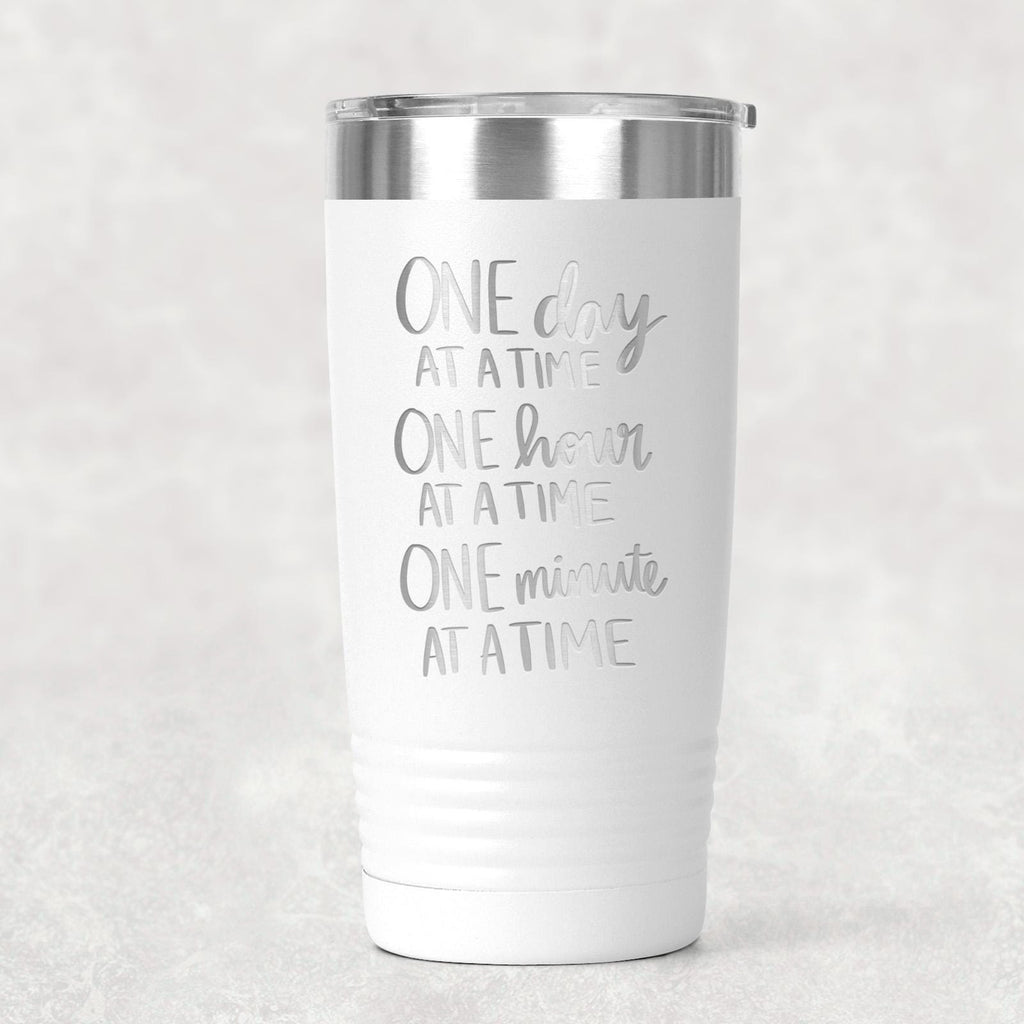 White stainless steel tumbler with “One day at a time” motivational text