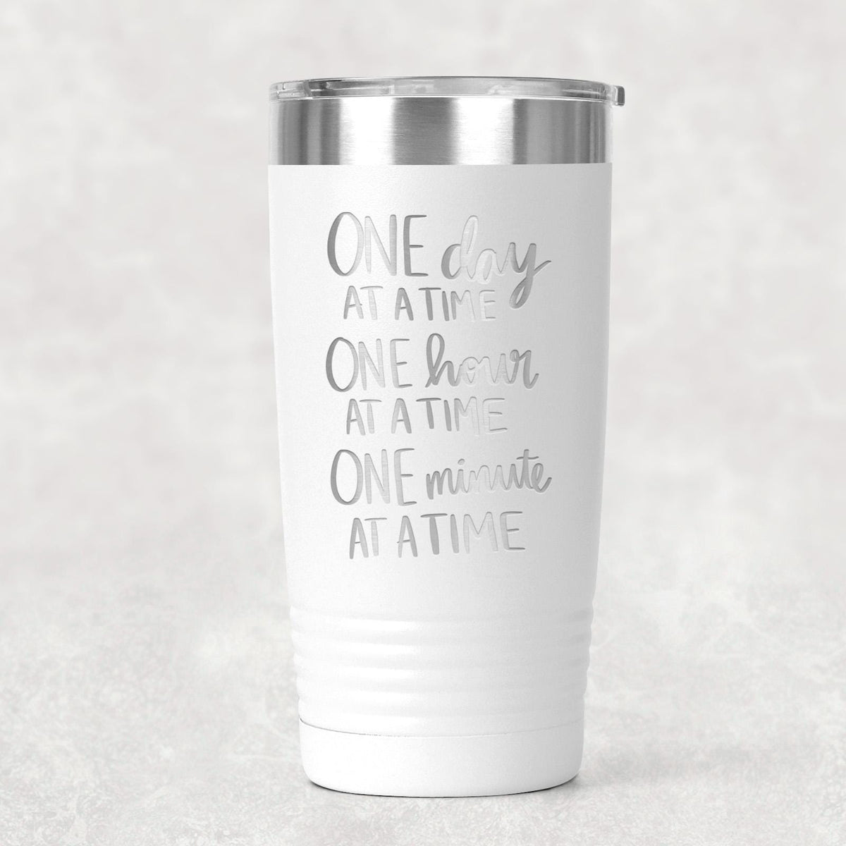 White stainless steel tumbler with “One day at a time” motivational text