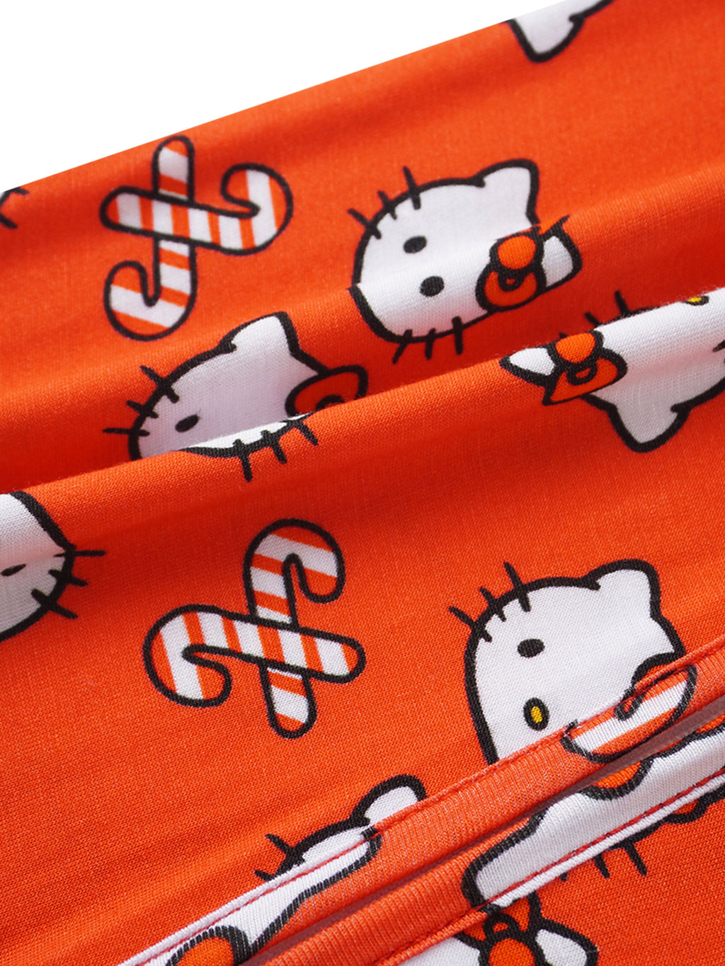 Red Hello Kitty romper fabric close-up with allover cat and music icon print