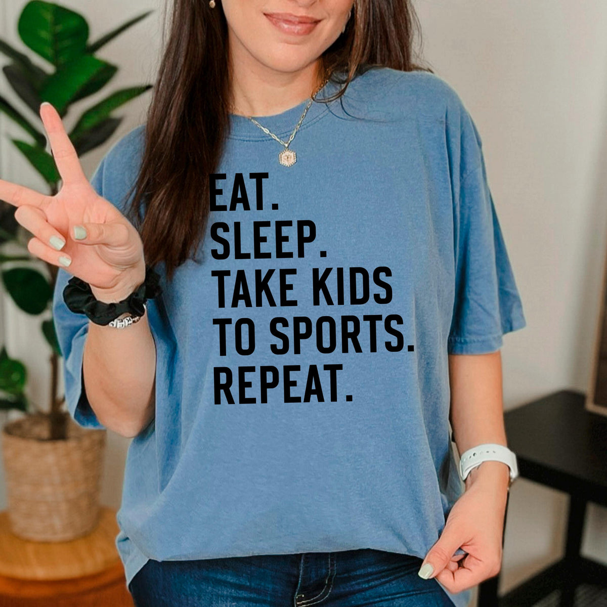 Blue unisex graphic tee with black text: EAT SLEEP TAKE KIDS TO SPORTS REPEAT.