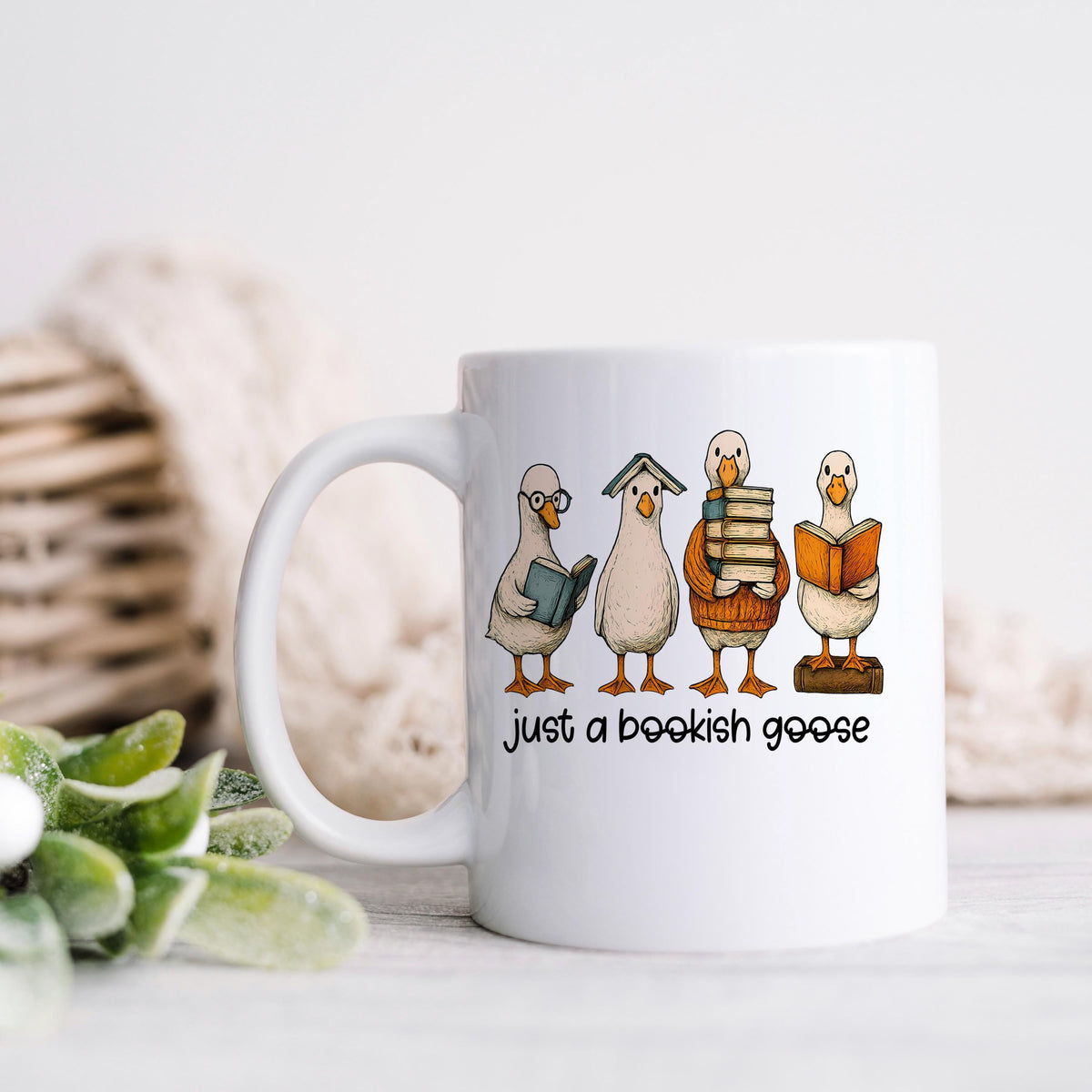 White coffee mug with bookish goose cartoon scene and "just a bookish goose"