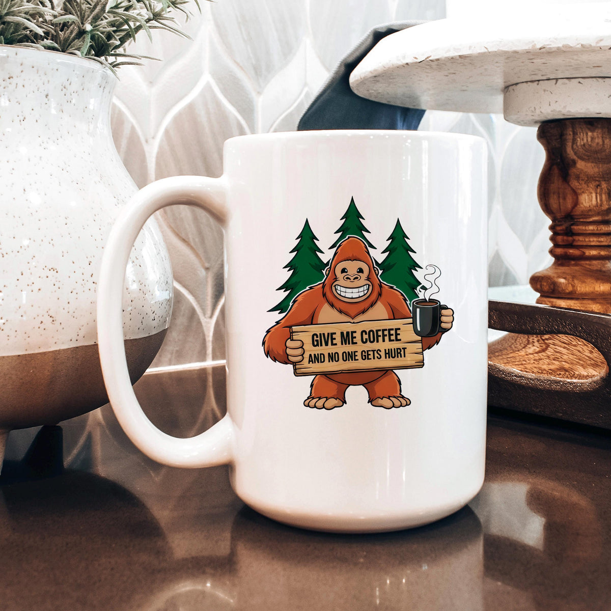 White ceramic coffee mug with Bigfoot graphic holding sign and steaming cup.
