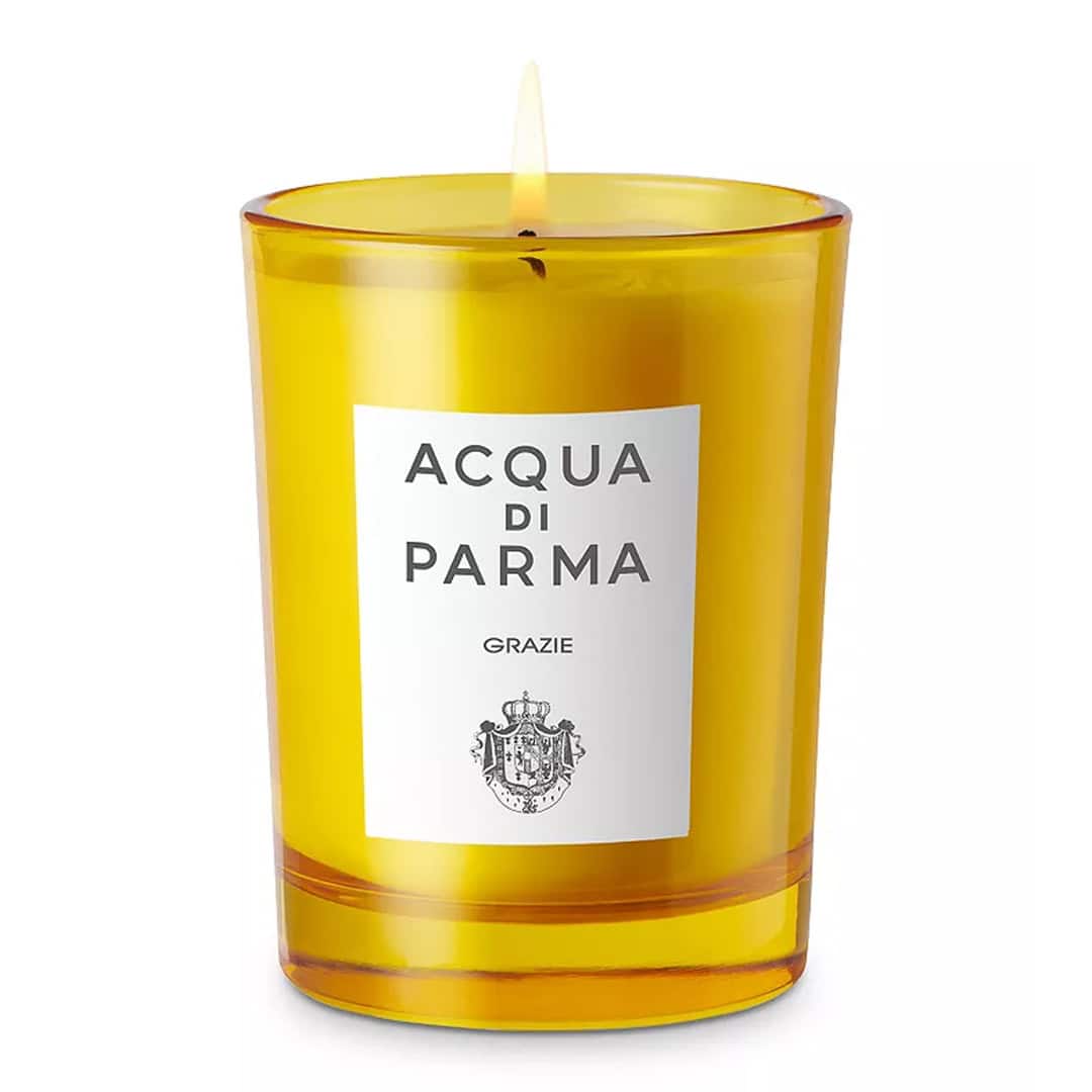 Amber scented candle in clear glass with branded label and lit wick