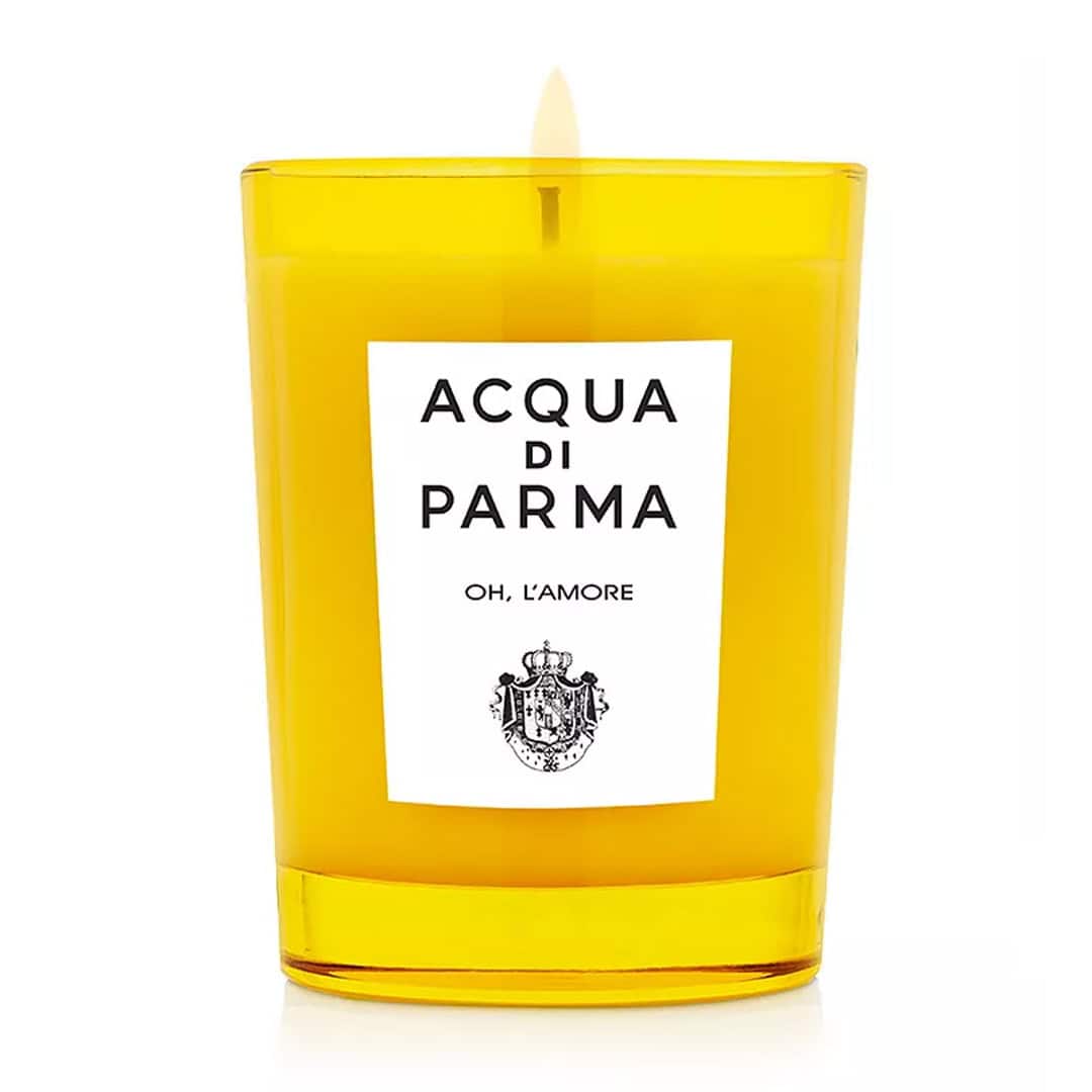 Yellow glass jar candle with ACQUA DI PARMA label and visible wick flame