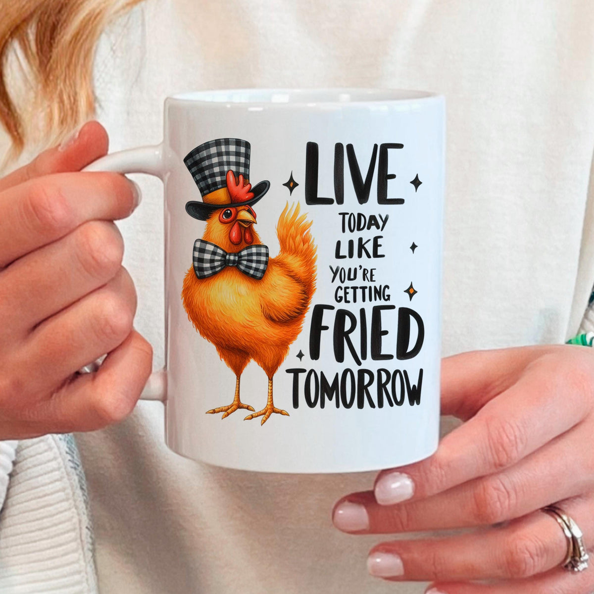 Hand holding white ceramic mug with orange cartoon chicken and LIVE…FRIED TOMORROW text