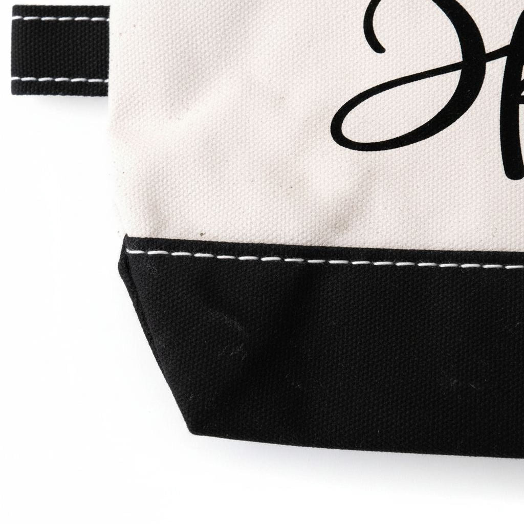 Beige-and-black canvas pouch corner with contrast stitching and partial 'anyone' lettering.