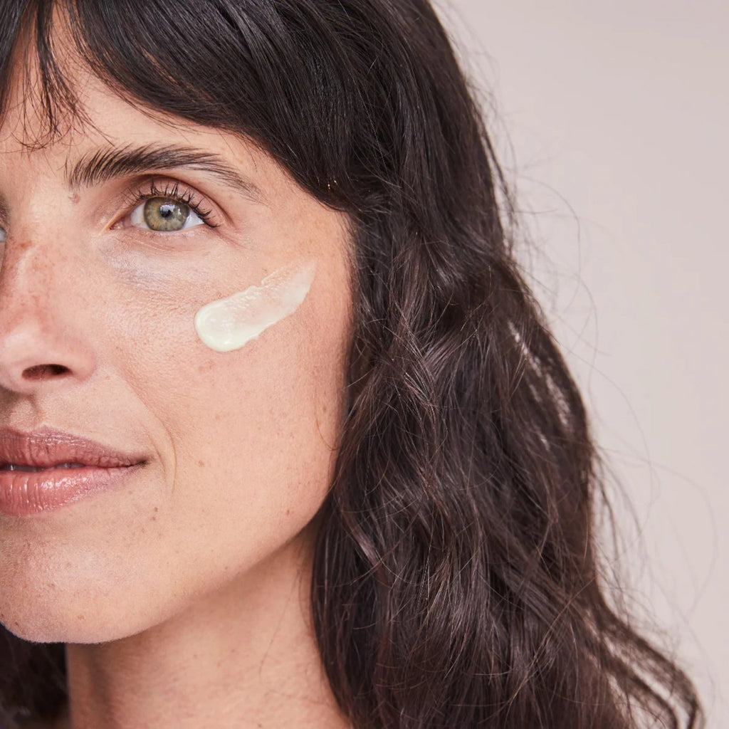 Retinol serum on cheek with pale cream smear, skincare application close-up