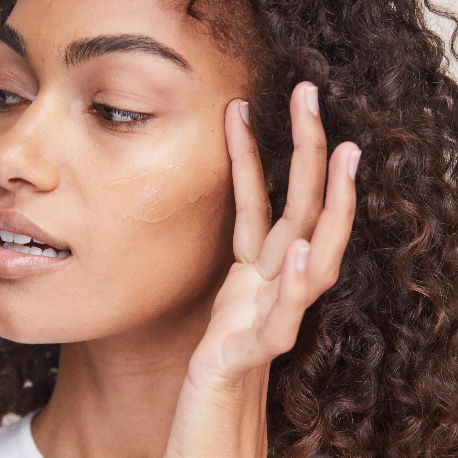 Moisturizing cream applied to cheek and near eye with fingers